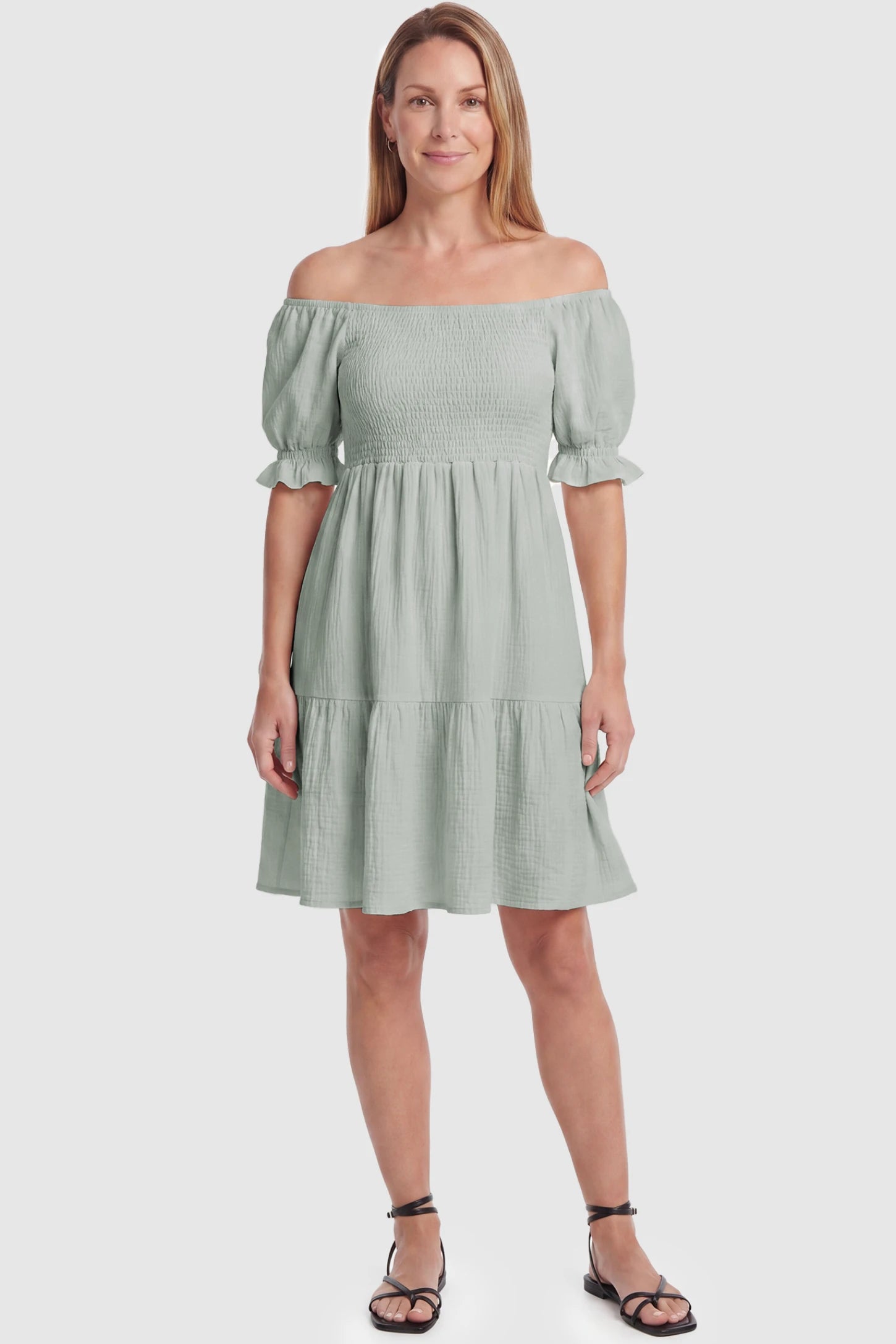Smocked Off-Shoulder Empire Waist Maternity Short Dress Smocked off-shoulder empire waist maternity short dress in light green with smocked bodice detail, front view on postpartum model