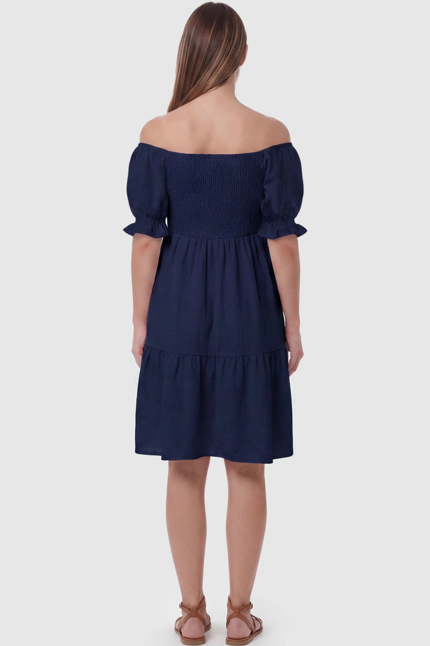 Smocked Off-Shoulder Empire Waist Maternity Short Dress Smocked off-shoulder empire waist maternity short dress in navy blue with short puff sleeve, back view on pregnant model