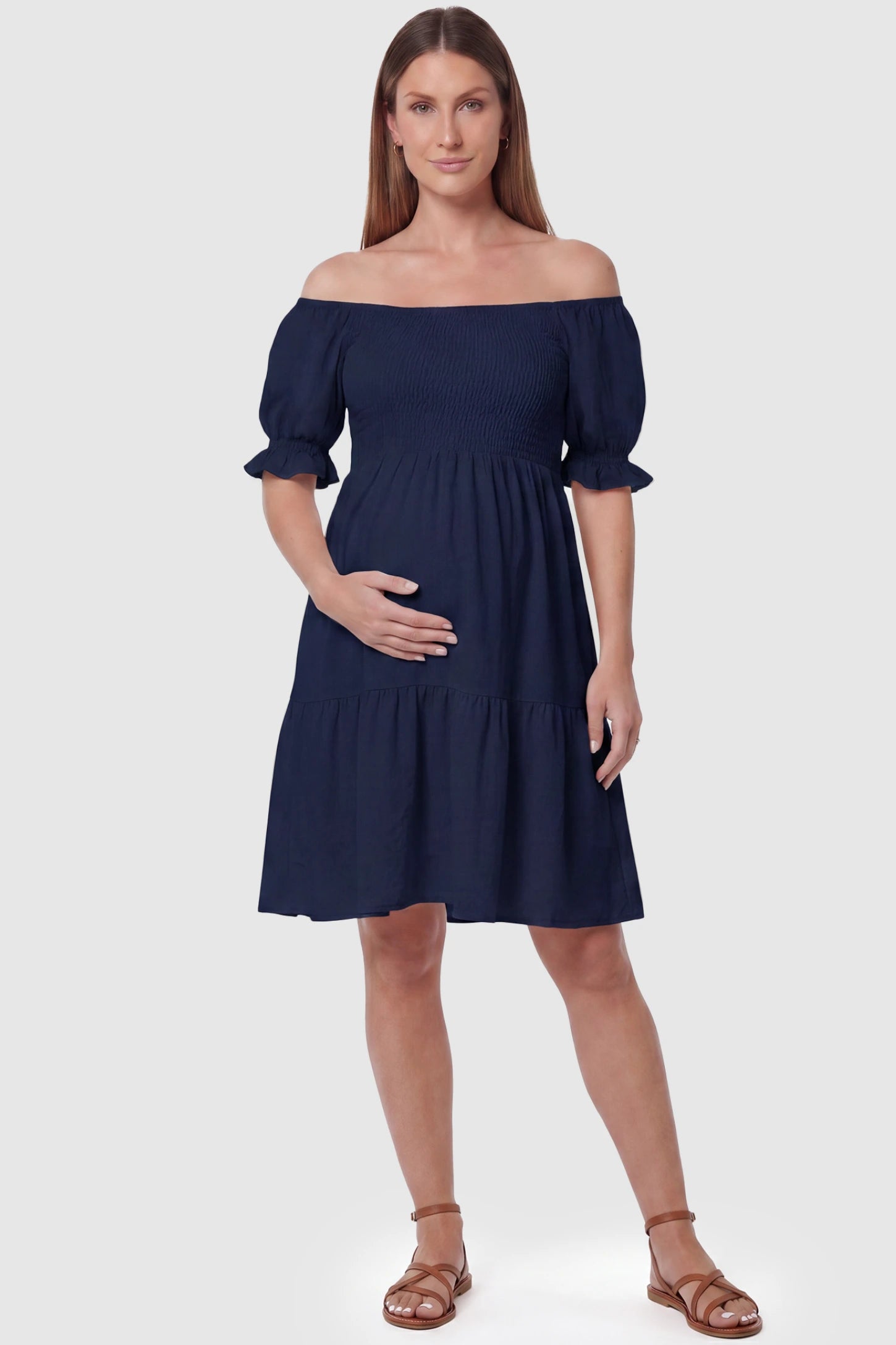Smocked Off-Shoulder Empire Waist Maternity Short Dress Smocked off-shoulder empire waist maternity short dress in navy blue with smocked bodice detail, front view on pregnant model