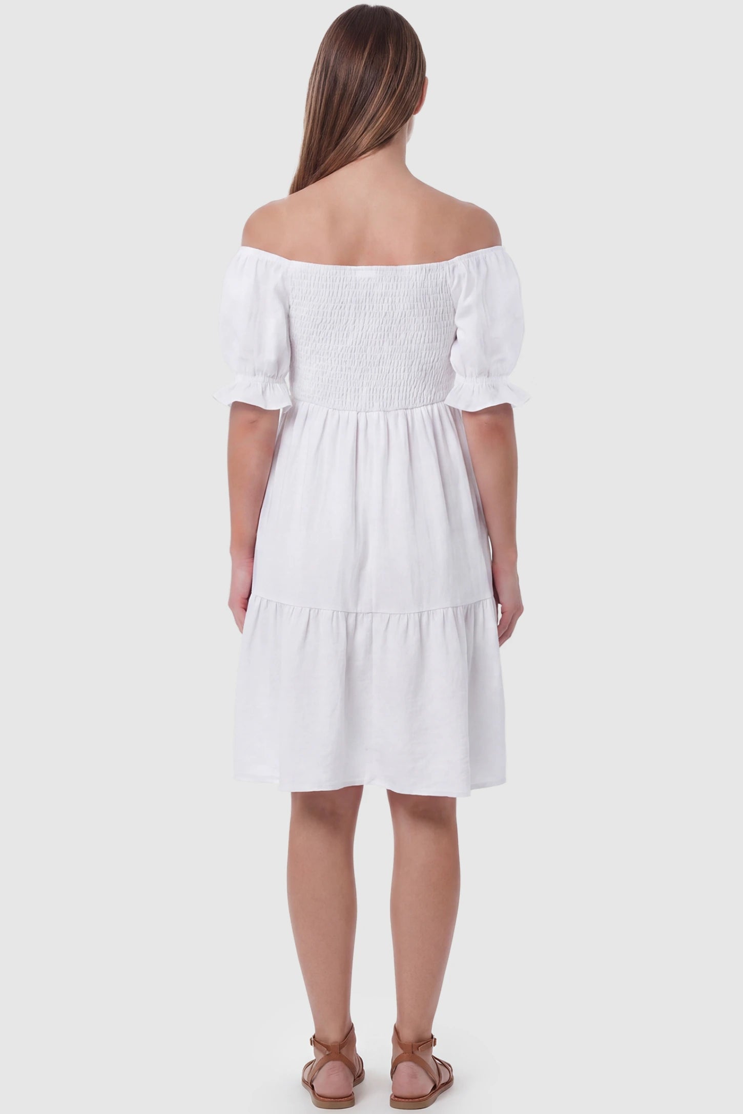 Smocked Off-Shoulder Empire Waist Maternity Short Dress Smocked off-shoulder empire waist maternity short dress in white with short puff sleeve, back view on pregnant model