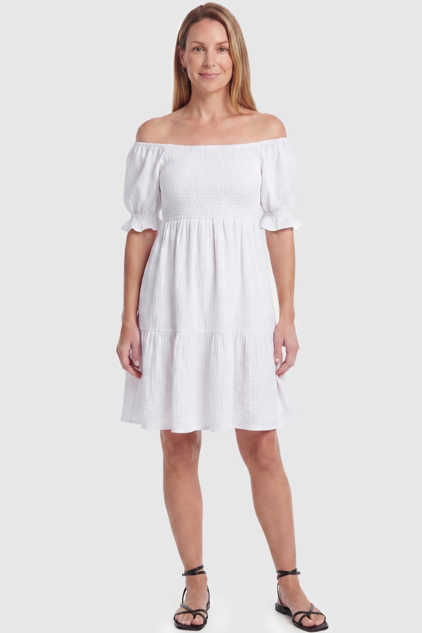 Smocked Off-Shoulder Empire Waist Maternity Short Dress Smocked off-shoulder empire waist maternity short dress in white with smocked bodice detail, front view on postpartum model