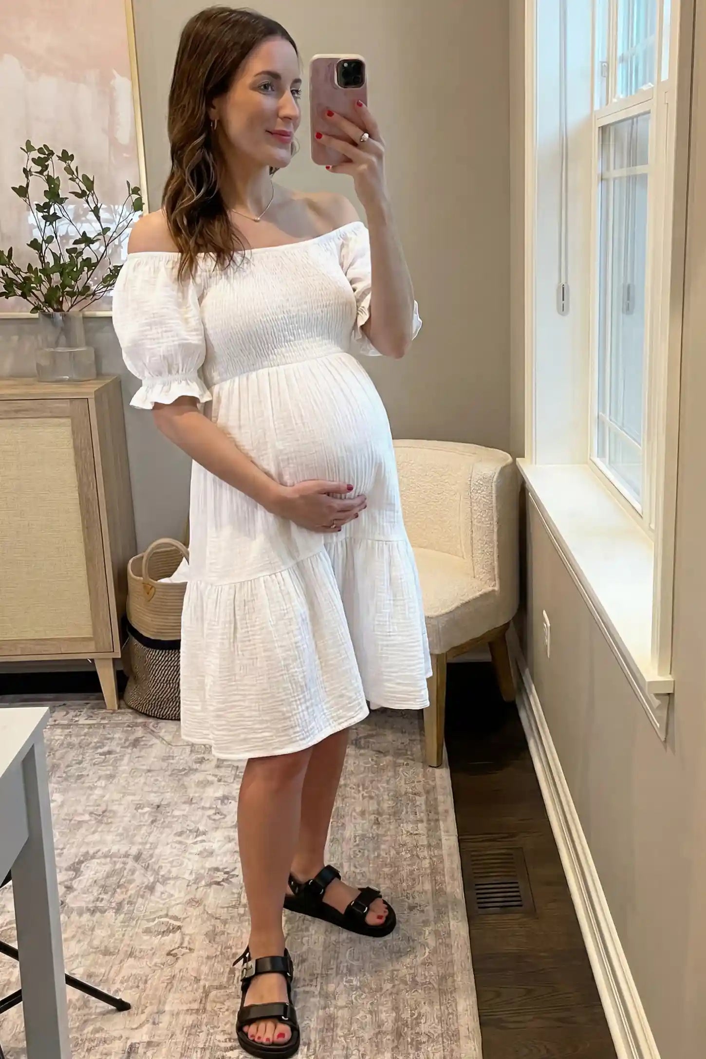 Smocked Off-Shoulder Empire Waist Maternity Short Dress Smocked off-shoulder empire waist maternity short dress in white with smocked bodice detail, front view on pregnant model