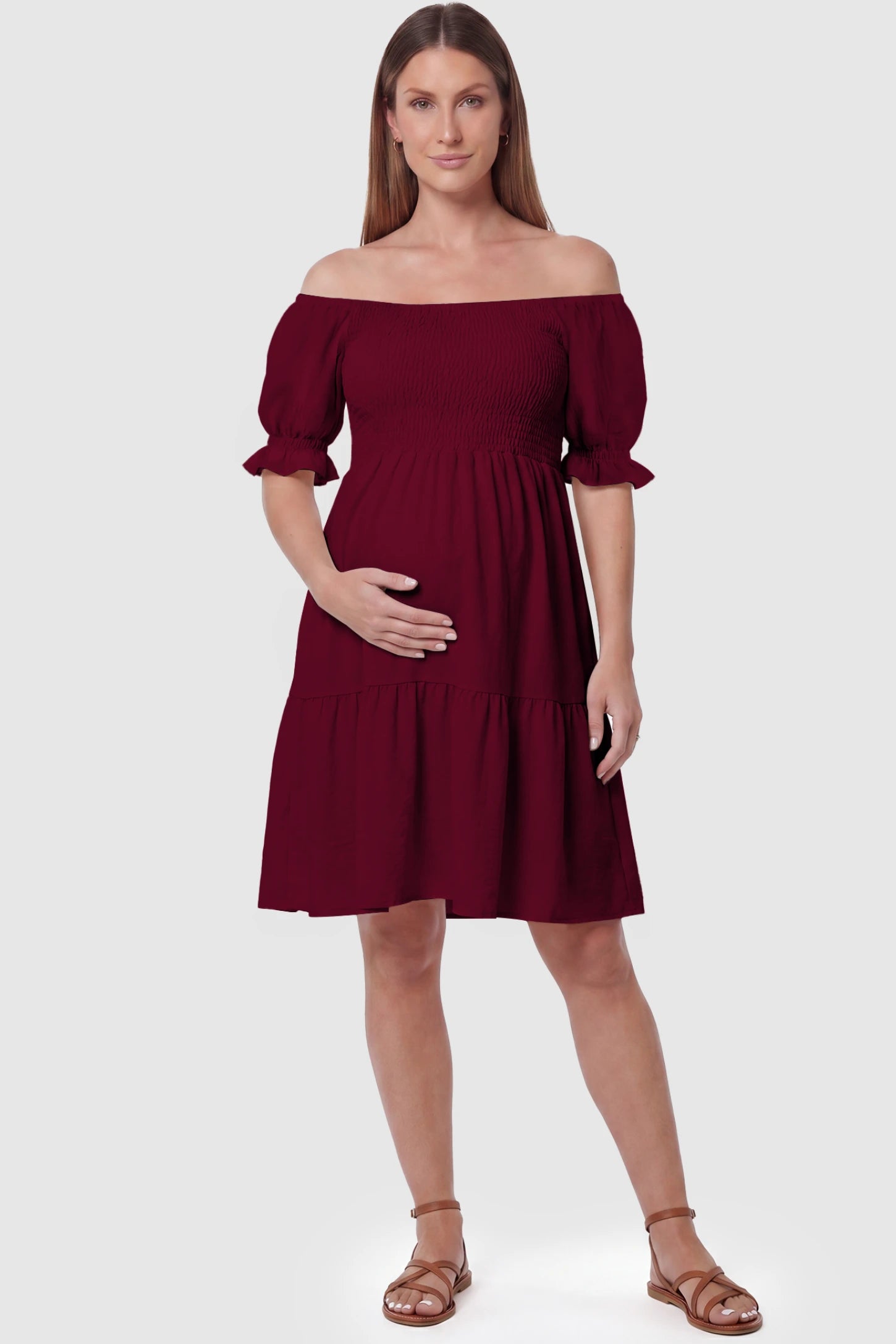 Smocked Off-Shoulder Empire Waist Maternity Short Dress Smocked off-shoulder empire waist maternity short dress in wine red with smocked bodice detail, front view on pregnant model