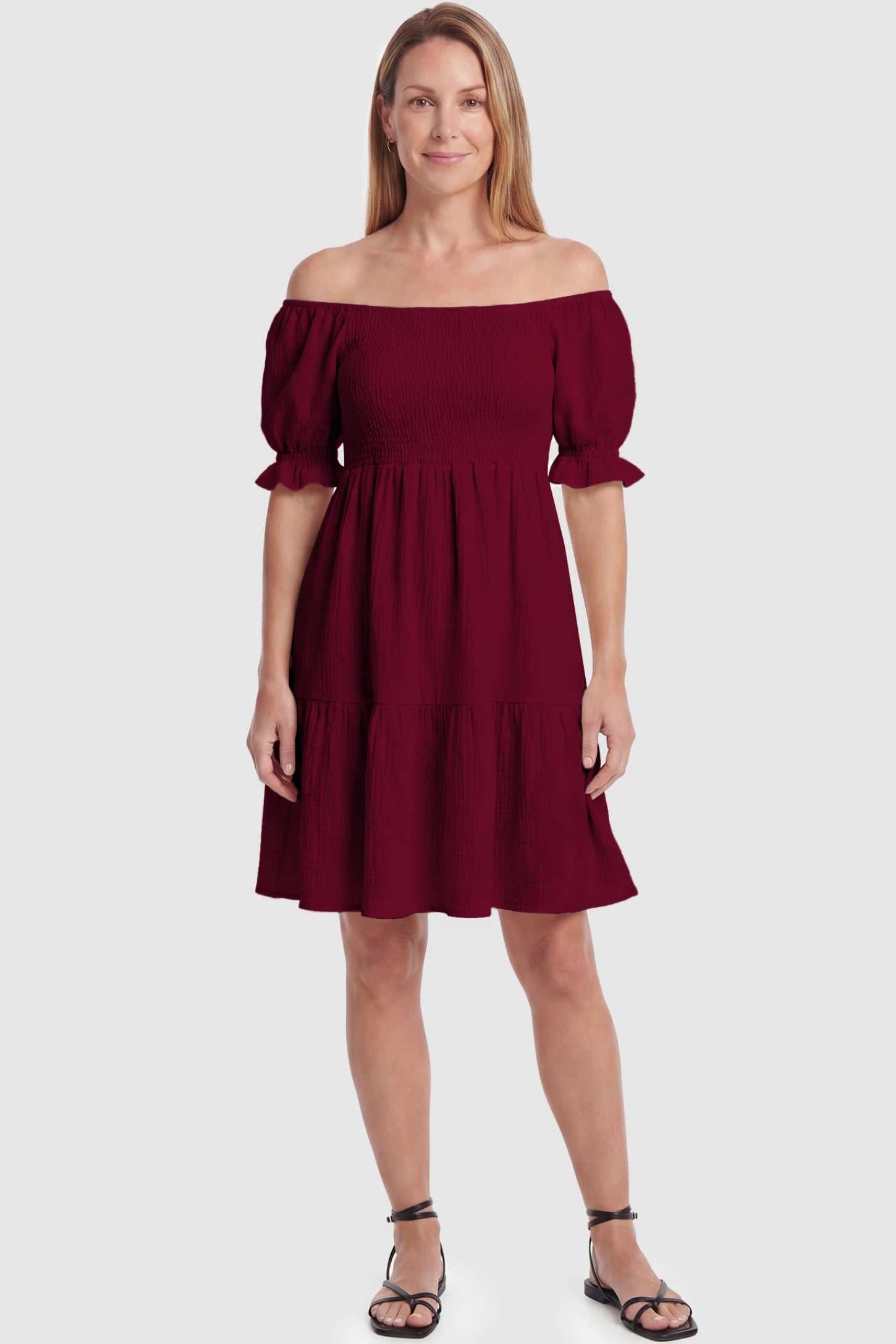 Smocked Off-Shoulder Empire Waist Maternity Short Dress Smocked off-shoulder empire waist maternity short dress in wine red with smocked bodice detail, front view on postpartum model