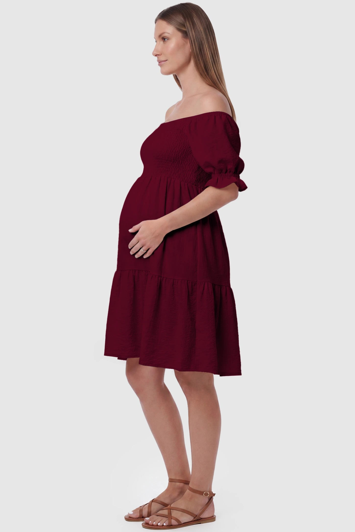 Smocked Off-Shoulder Empire Waist Maternity Short Dress Smocked off-shoulder empire waist maternity short dress in wine red with bump-friendly empire waist fit, side view on pregnant model