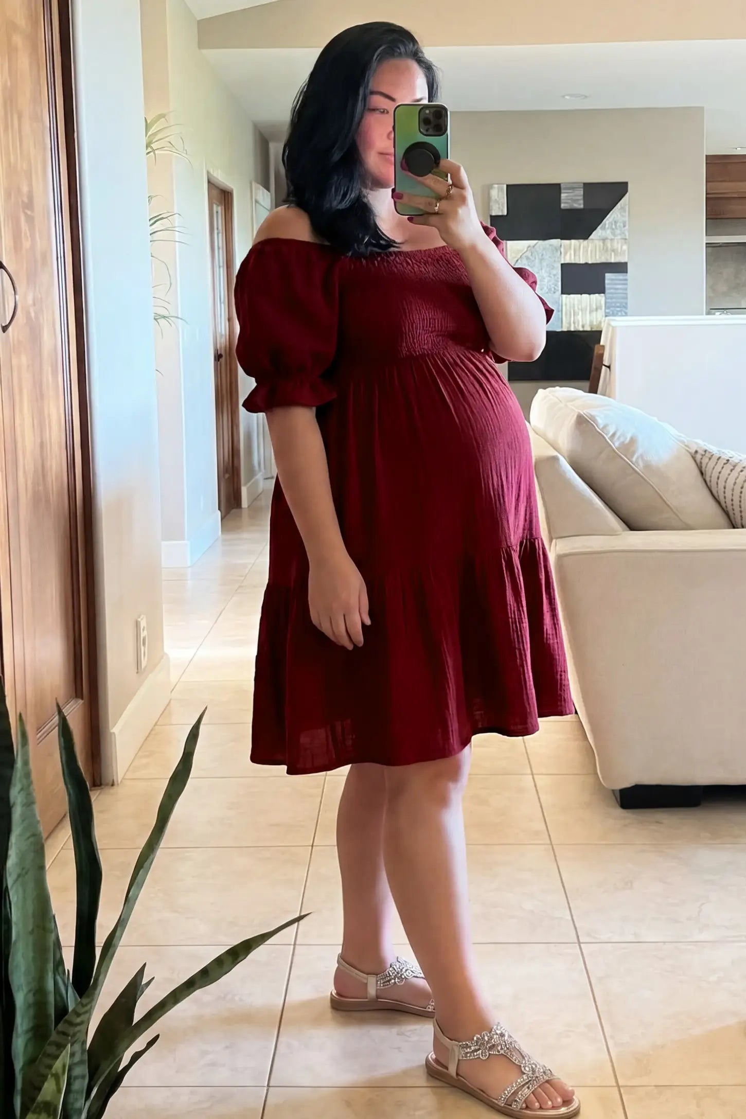 Smocked Off-Shoulder Empire Waist Maternity Short Dress Smocked off-shoulder empire waist maternity short dress in wine red with smocked bodice detail, side view on pregnant model