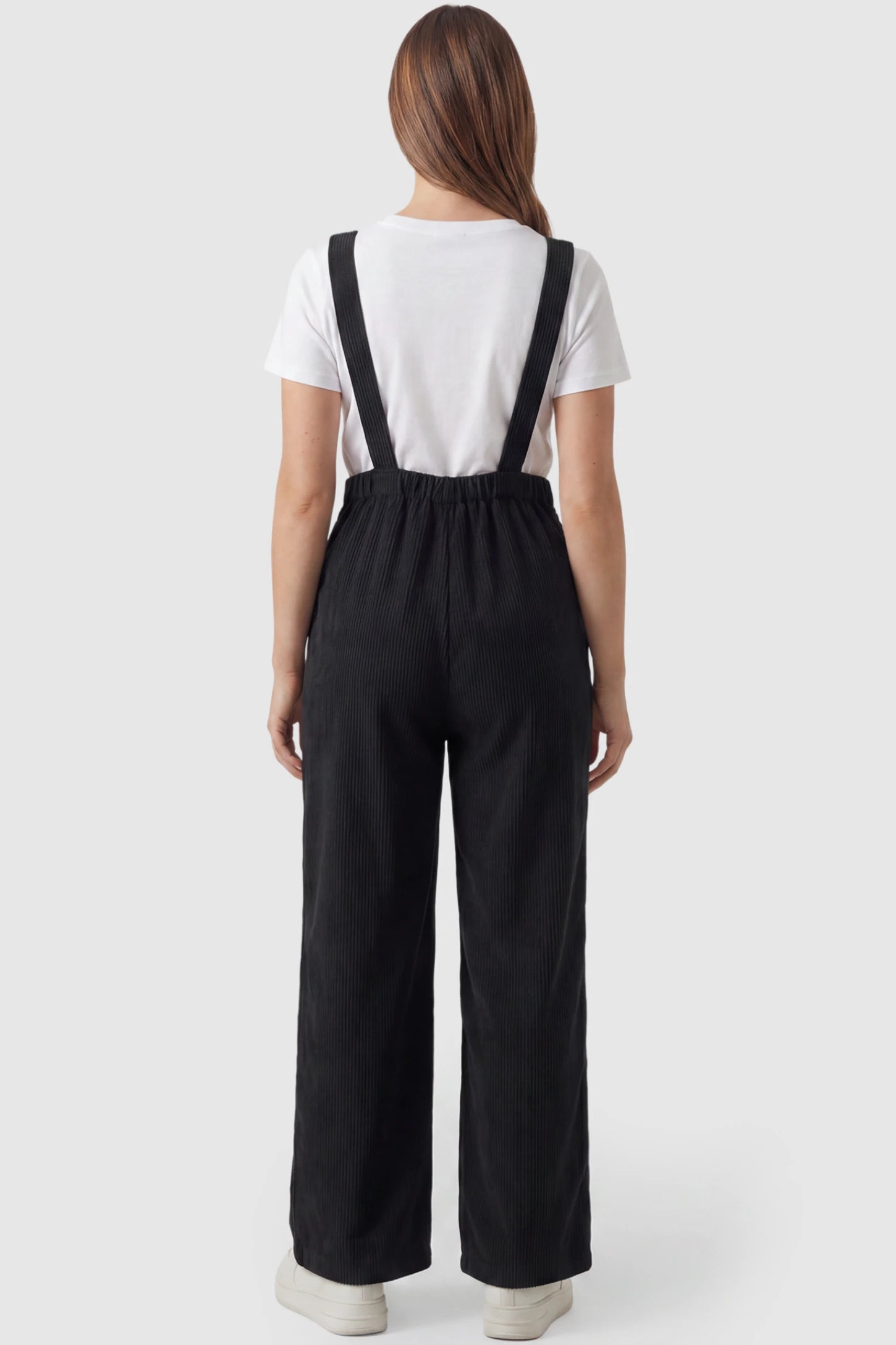 Corduroy Wide Leg Maternity Jumpsuit Corduroy Wide-Leg Maternity Jumpsuit in Black featuring a relaxed wide-leg silhouette on a pregnant model, back view.
