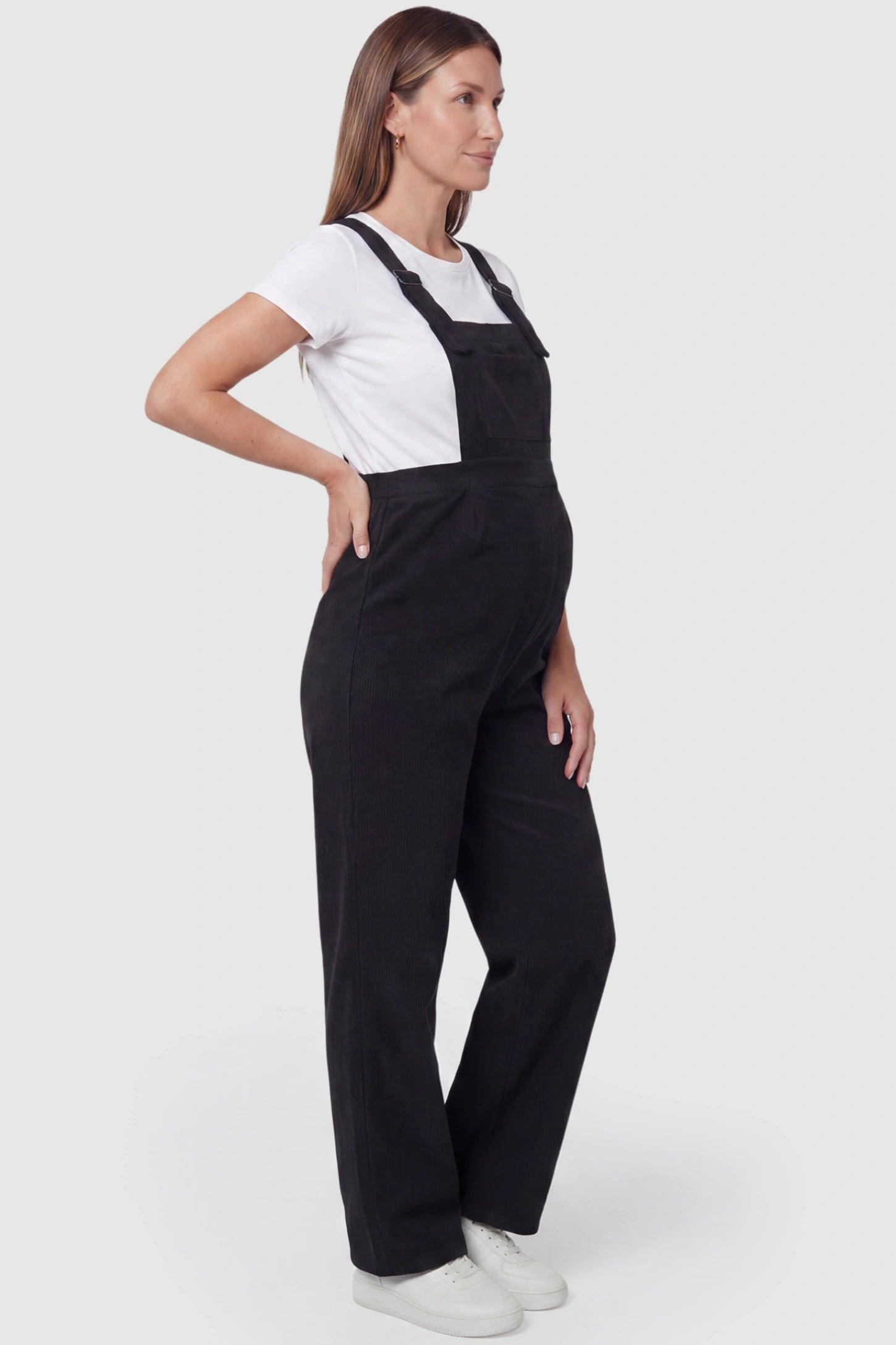 Corduroy Wide Leg Maternity Jumpsuit Corduroy Wide-Leg Maternity Jumpsuit in Black featuring a relaxed wide-leg silhouette on a pregnant model, side view.