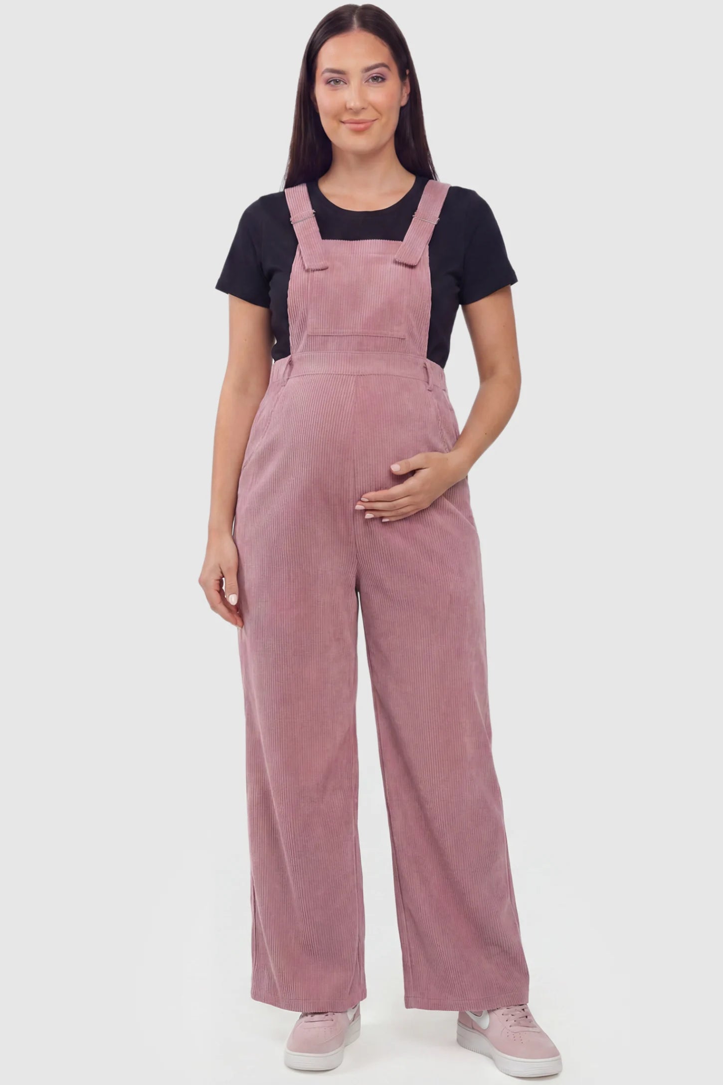 Corduroy Wide Leg Maternity Jumpsuit Corduroy Wide-Leg Maternity Jumpsuit in Pink featuring a relaxed wide-leg silhouette on a plus size pregnant model, front view.