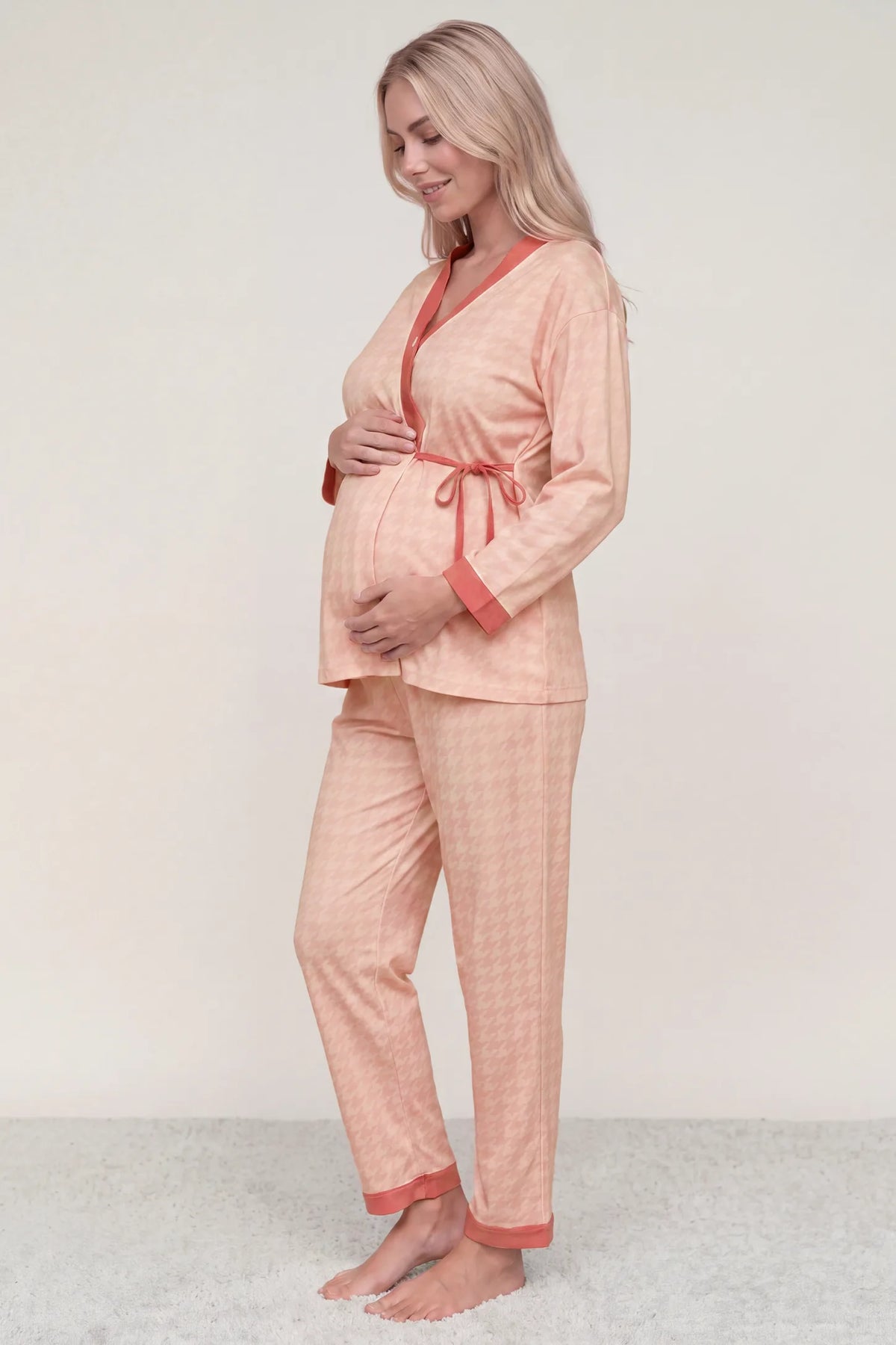Cotton Houndstooth Nursing Pajama Set Cotton Houndstooth Nursing Pajama Set in Pink Houndstooth featuring side bump space, relaxed kimono-inspired fit, and soft pink piping on a pregnant model, side profile view.
