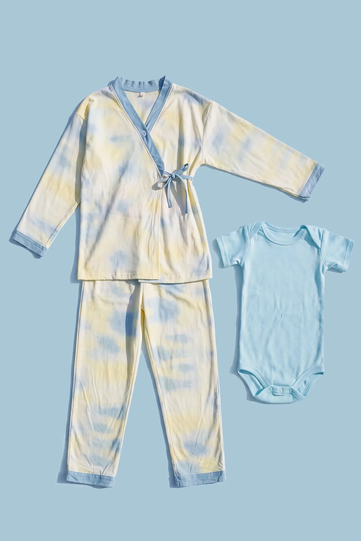 Cotton Tie-Dye Maternity & Nursing Pajama Set Cotton Tie-Dye Maternity & Nursing Pajama Set in Blue Tie-Dye featuring complete two-piece sleepwear layout with kimono wrap top, long pants, and matching baby onesie displayed in a flat lay view.