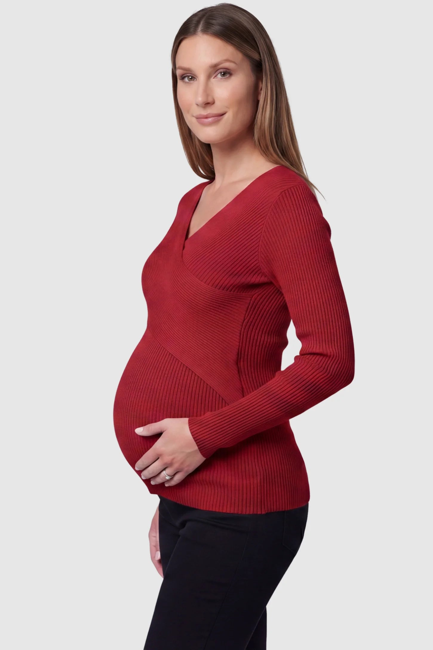 Cross-Over Ribbed Knit Maternity & Nursing Top Cross-Over Ribbed Knit Maternity & Nursing Top in Red featuring a wrap neckline and textured finish on a pregnant model, side view.