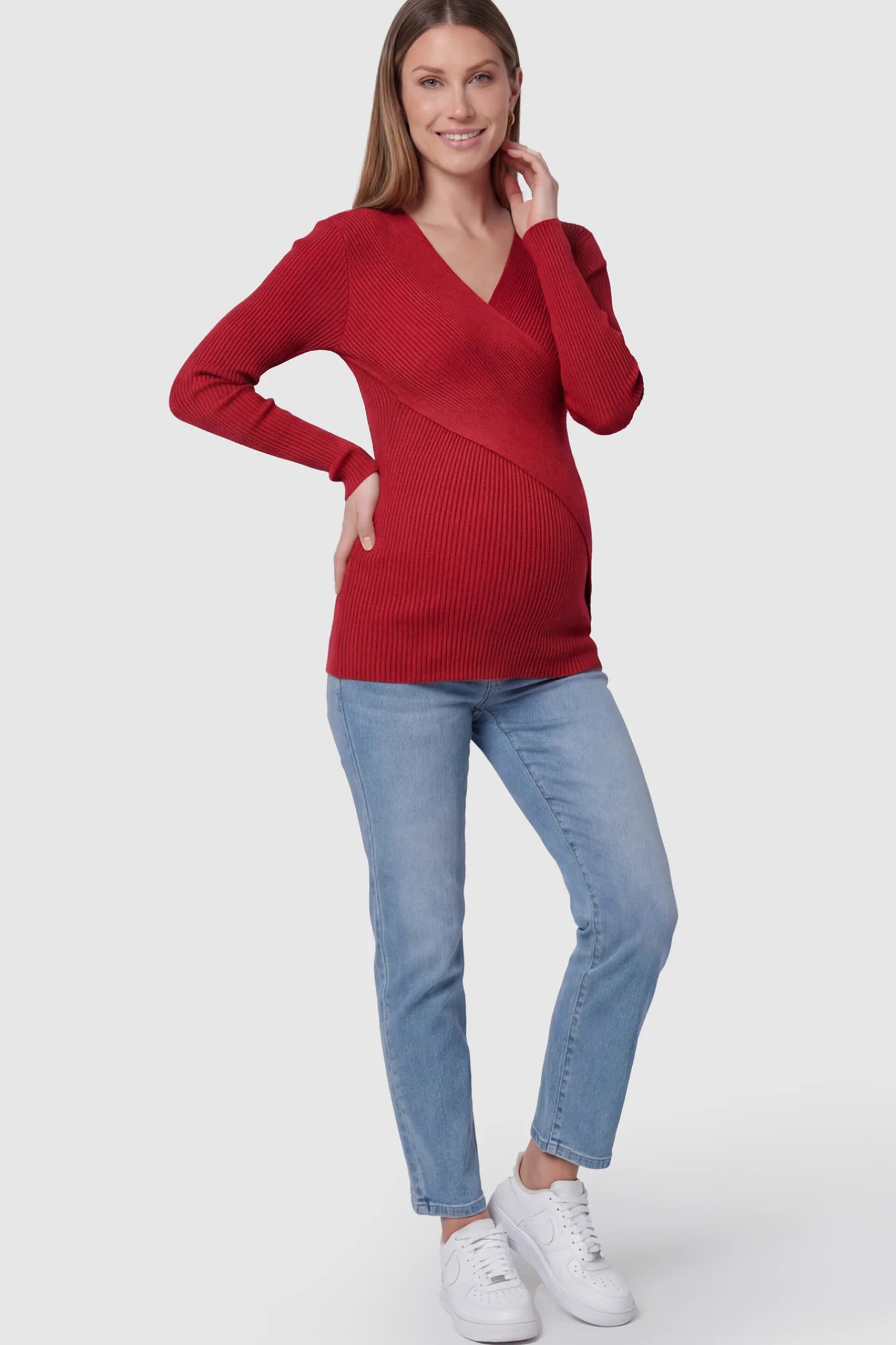 Cross-Over Ribbed Knit Maternity & Nursing Top Cross-Over Ribbed Knit Maternity & Nursing Top in Red featuring a wrap neckline and textured finish on a pregnant model, full body shot.