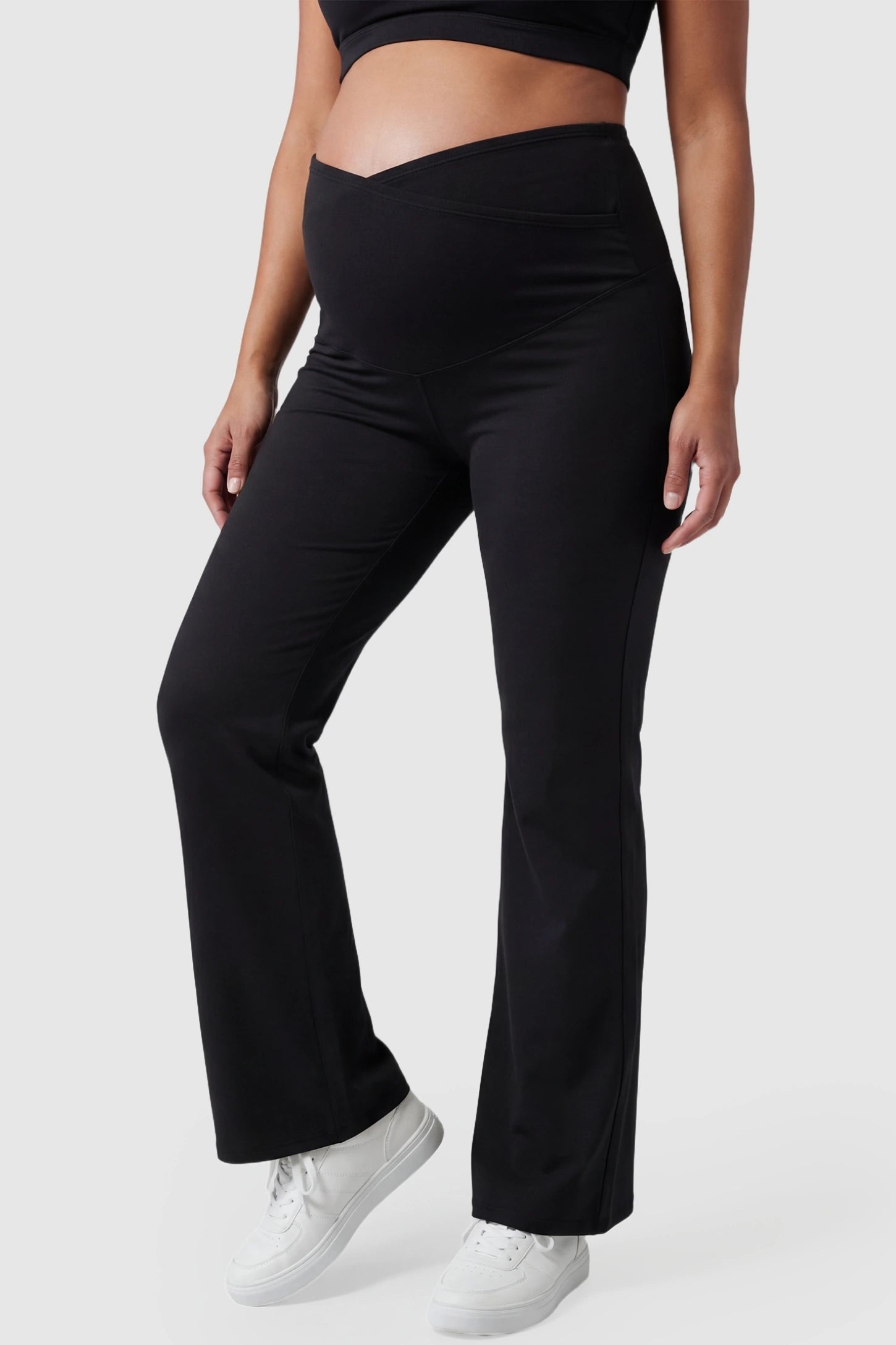 Cross Over High-Waisted Wide-Leg Maternity Pants in Black featuring a supportive V-waistband on a pregnant model from the front.