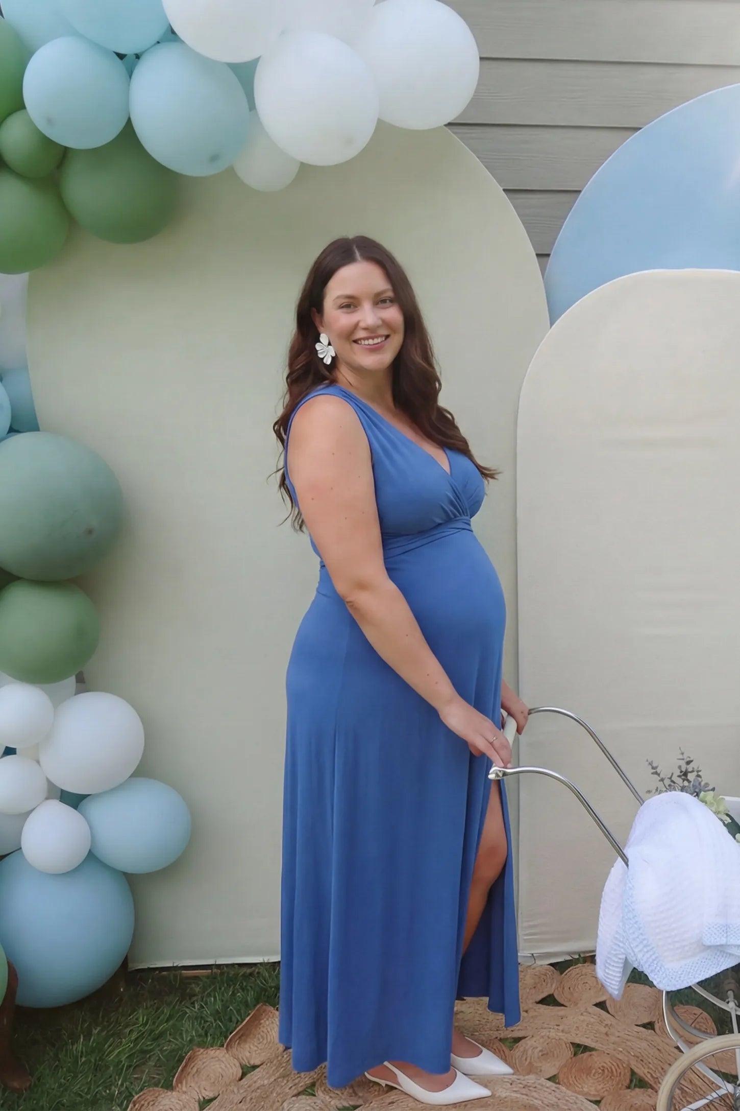 V-Neck Cross-Back Maxi Maternity Dress V-Neck Cross-Back Maxi Maternity Dress in Blue featuring a flattering cinched empire waist on a pregnant model in a side view.