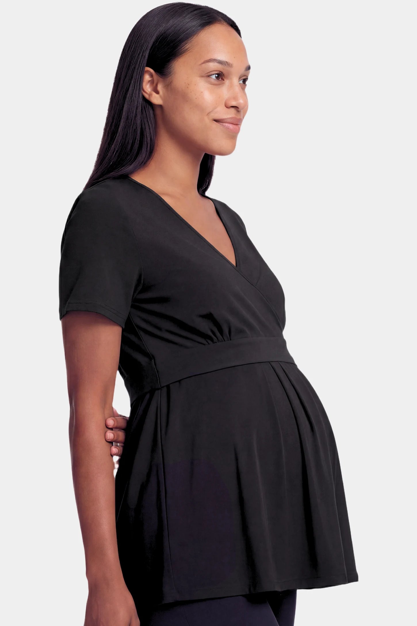Crossover Short Sleeve Maternity & Nursing Top Crossover Short Sleeve Maternity & Nursing Top in black featuring a crossover V-neck and empire waist on a pregnant model.