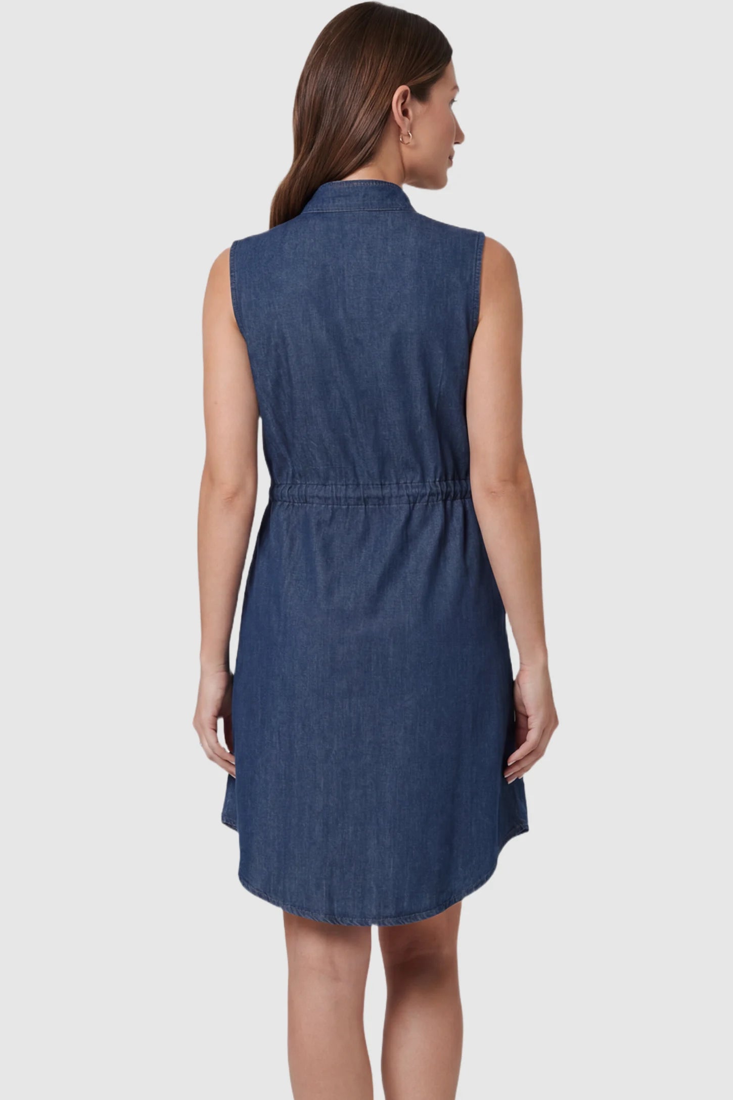 Denim Sleeveless Maternity & Nursing Shirt Dress Denim Sleeveless Maternity & Nursing Midi Shirt Dress in dark blue featuring sleeveless cut on a pregnant model showing back.
