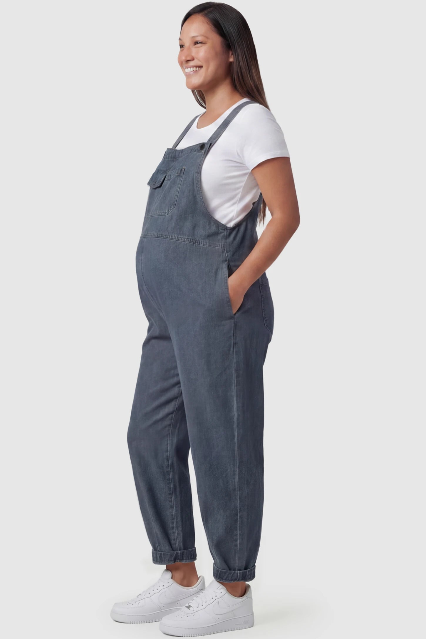 Wide Leg Denim Maternity Overalls Wide Leg Denim Maternity Overalls in blue with adjustable straps and relaxed fit on pregnant model side view.