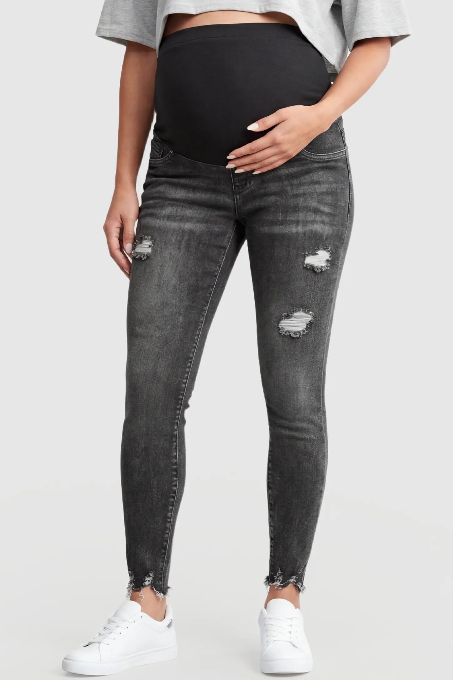 Frayed hem distressed cropped slim-fit maternity jeans in black with stretch belly panel, front view on pregnant model