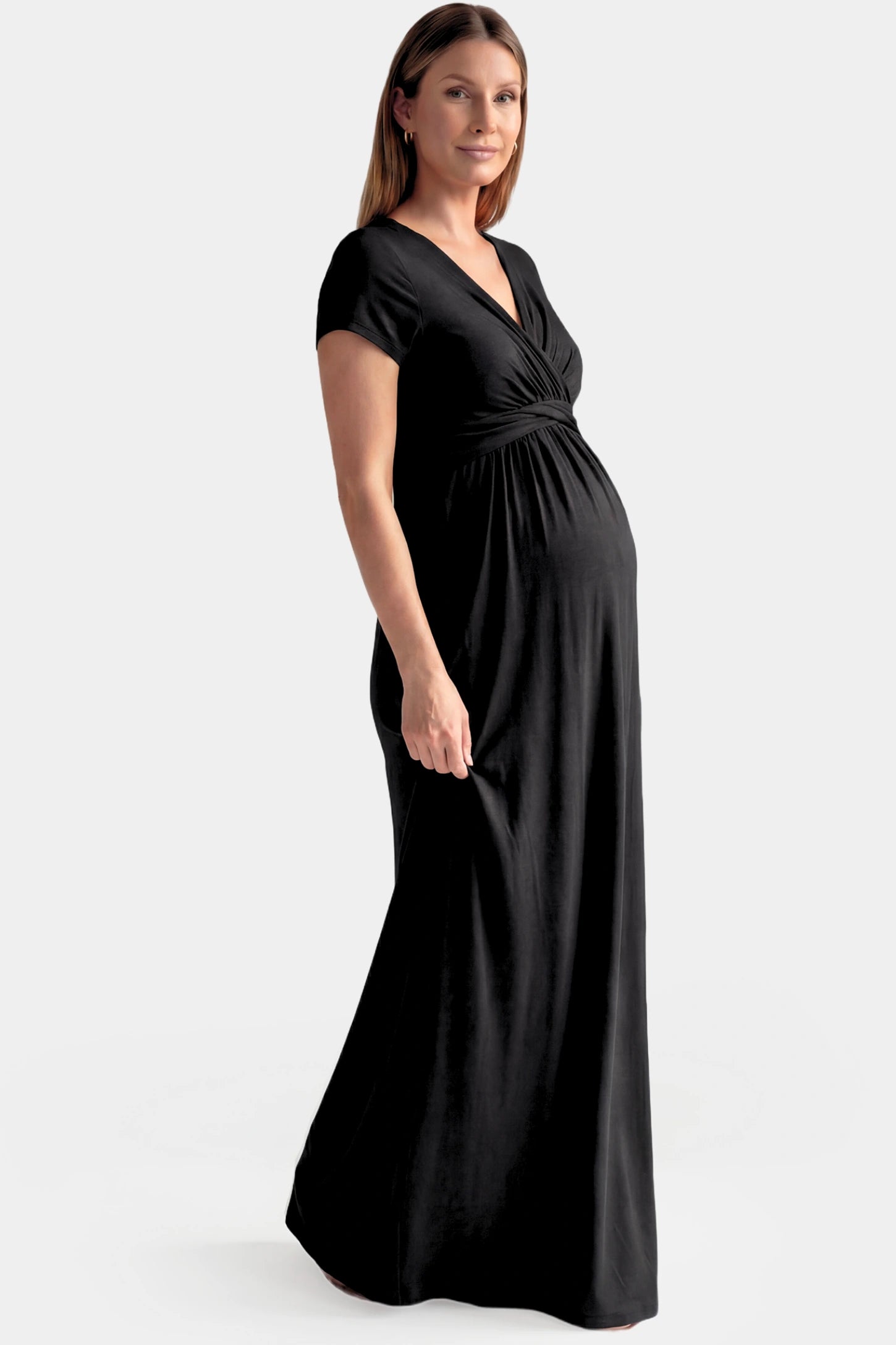 Crossover Draped Maternity & Nursing Maxi Dress Crossover Draped Maternity & Nursing Maxi Dress in black featuring a V-neck crossover design and flowy empire waist silhouette on a pregnant model.