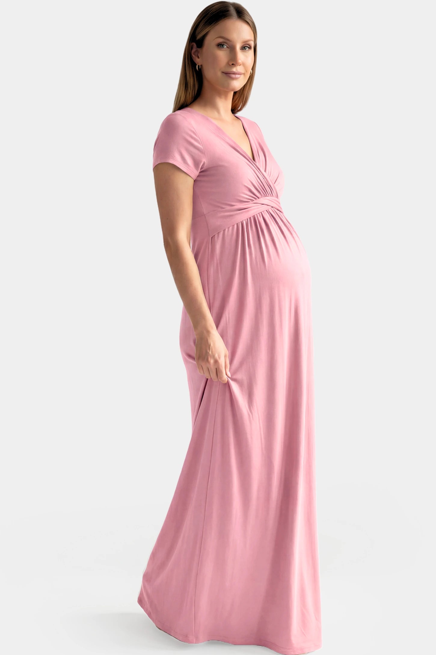 Crossover Draped Maternity & Nursing Maxi Dress Crossover Draped Maternity & Nursing Maxi Dress in pink featuring a V-neck crossover design and flowy empire waist silhouette on a pregnant model.