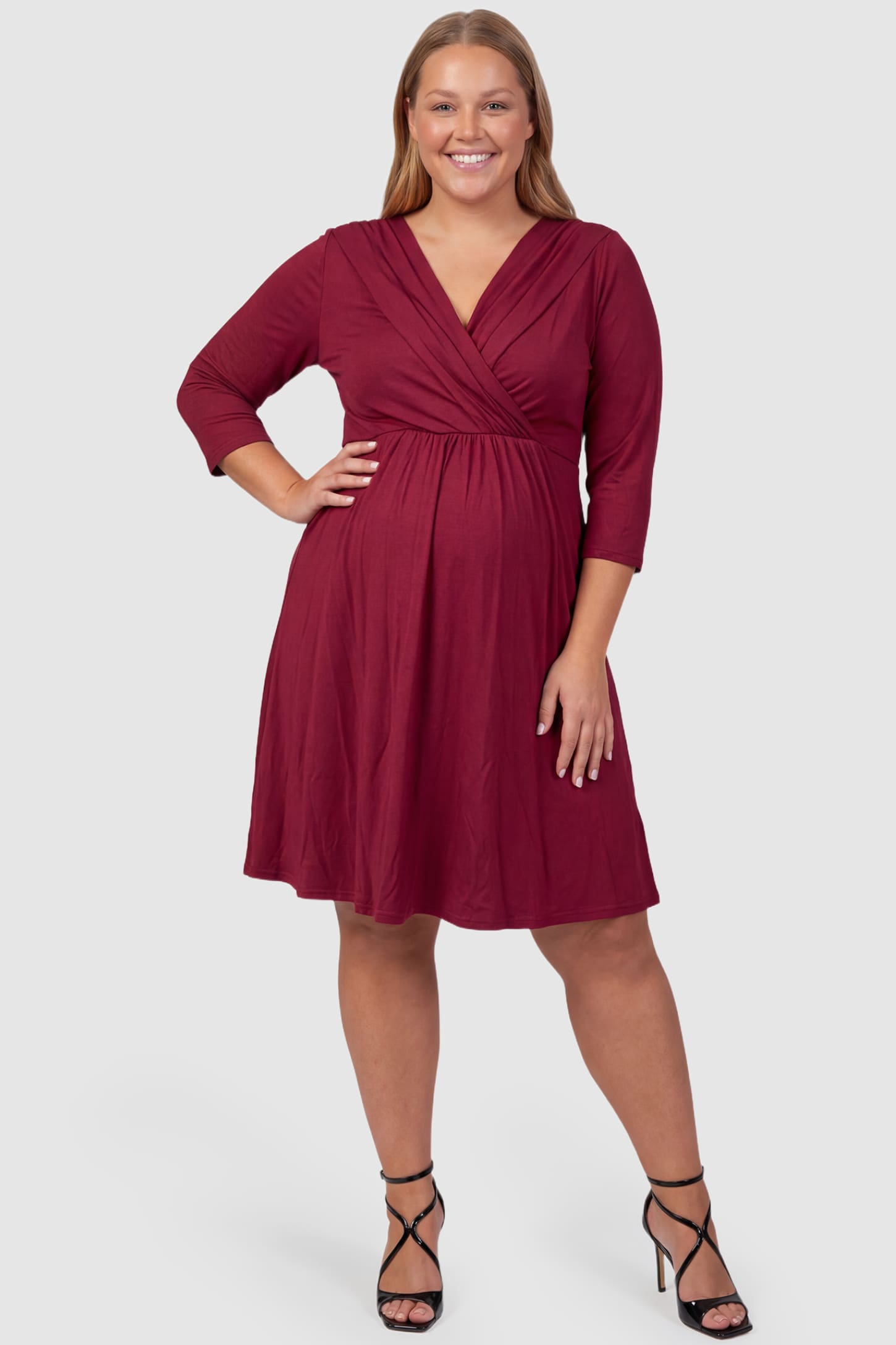 Crossover A-Line Maternity & Nursing Midi Dress Crossover A-Line Maternity & Nursing Midi Dress in red featuring wrap V-neck bodice and flowy midi skirt on plus size pregnant model.