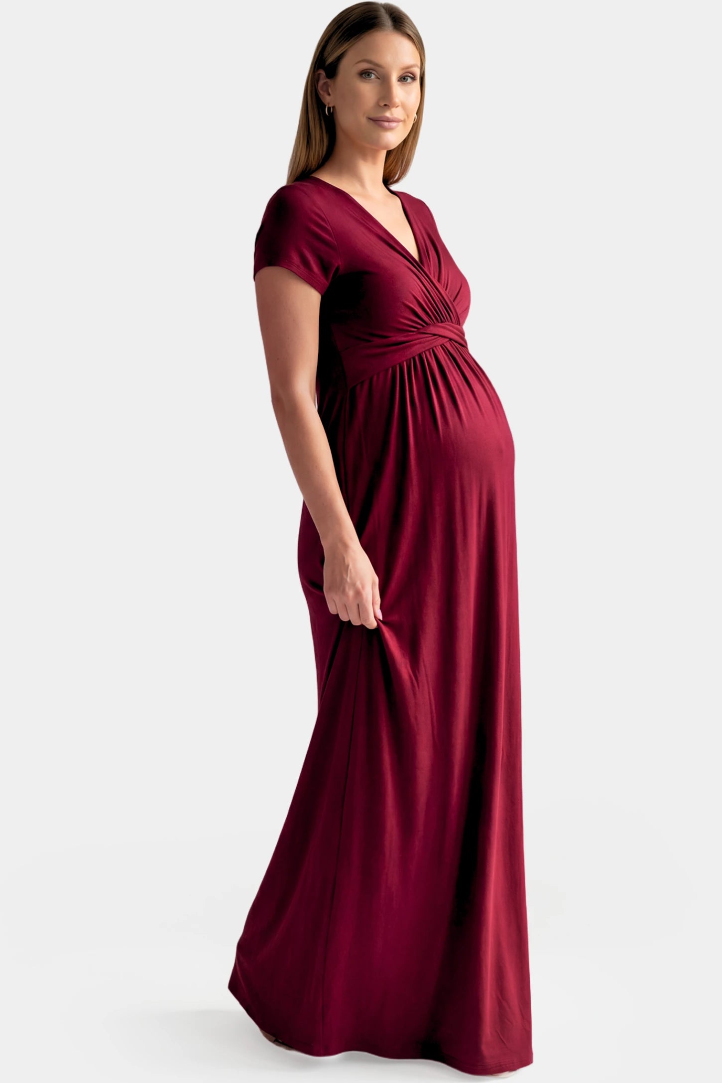 Crossover Draped Maternity & Nursing Maxi Dress Crossover Draped Maternity & Nursing Maxi Dress in red wine featuring a V-neck crossover design and flowy empire waist silhouette on a pregnant model.