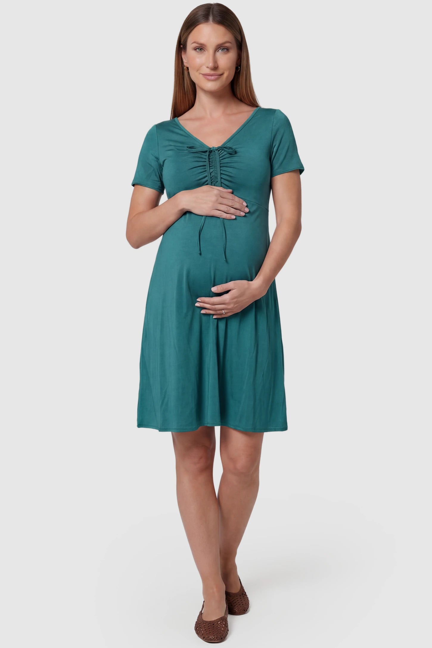 Drawstring Bow Front A‑Line Maternity Short Dress Drawstring bow front A-line maternity short dress in teal green with V-neckline and bow-tie front detail, front view on pregnant model
