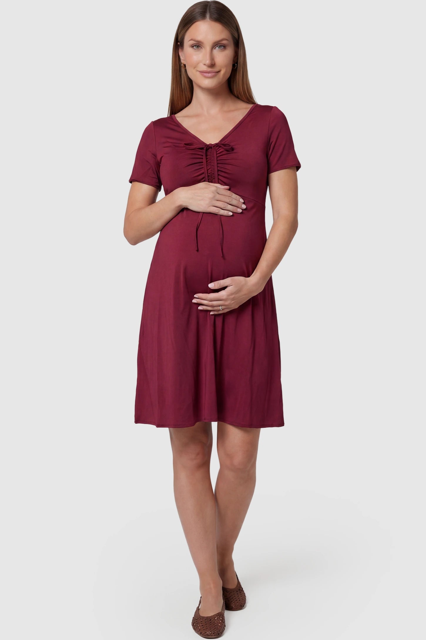 Drawstring Bow Front A‑Line Maternity Short Dress Drawstring bow front A-line maternity short dress in wine red with V-neckline and bow-tie front detail, front view on pregnant model