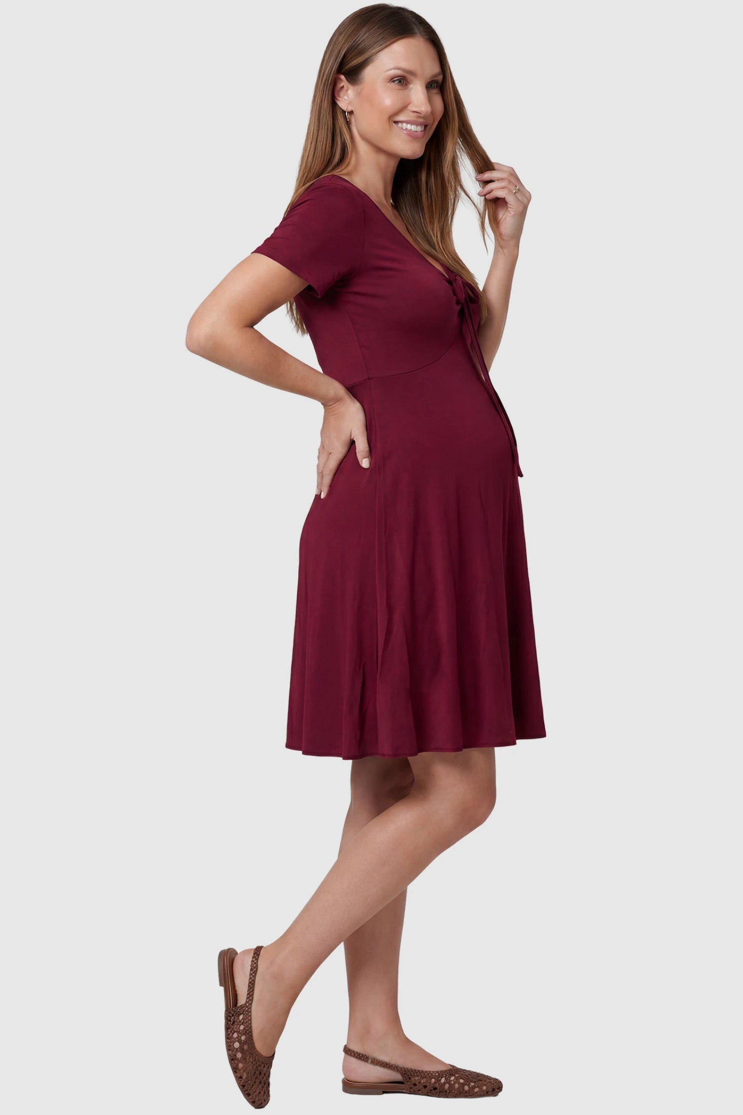 Drawstring Bow Front A‑Line Maternity Short Dress Drawstring bow front A-line maternity short dress in wine red with bump-friendly relaxed fit, side view on pregnant model