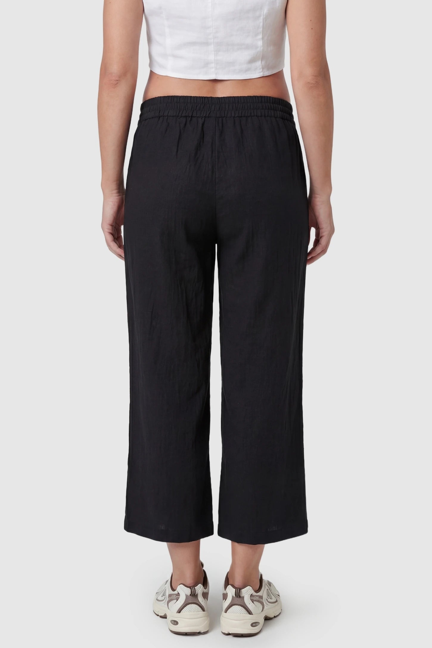 Elastic High Waisted Cropped Maternity Pants Elastic High Waisted Cropped Maternity Pants in Black featuring a wide leg cut and smooth stretch fabric on a pregnant model, back view.