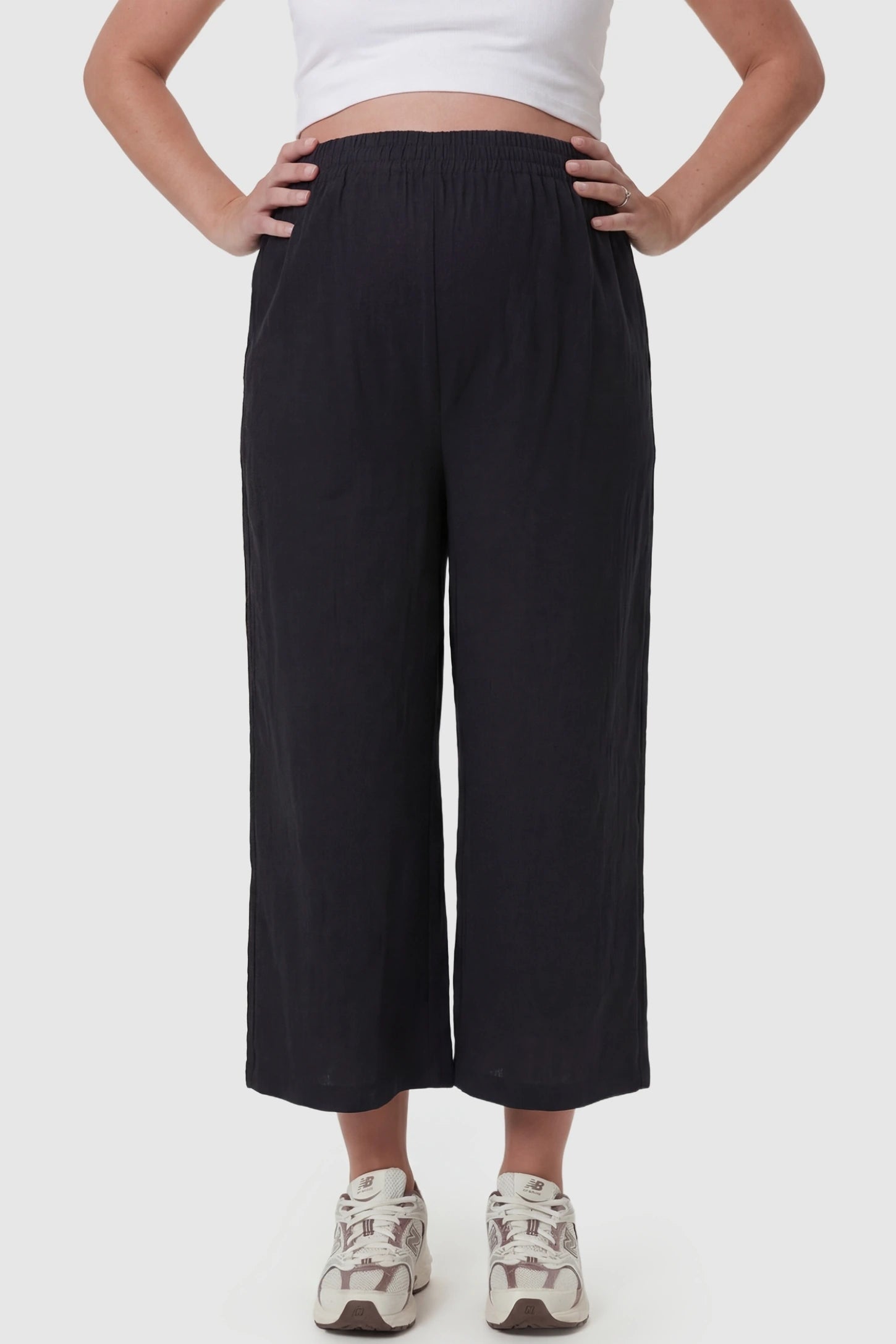 Elastic High Waisted Cropped Maternity Pants in Black featuring a supportive belly band on a pregnant model, front view.