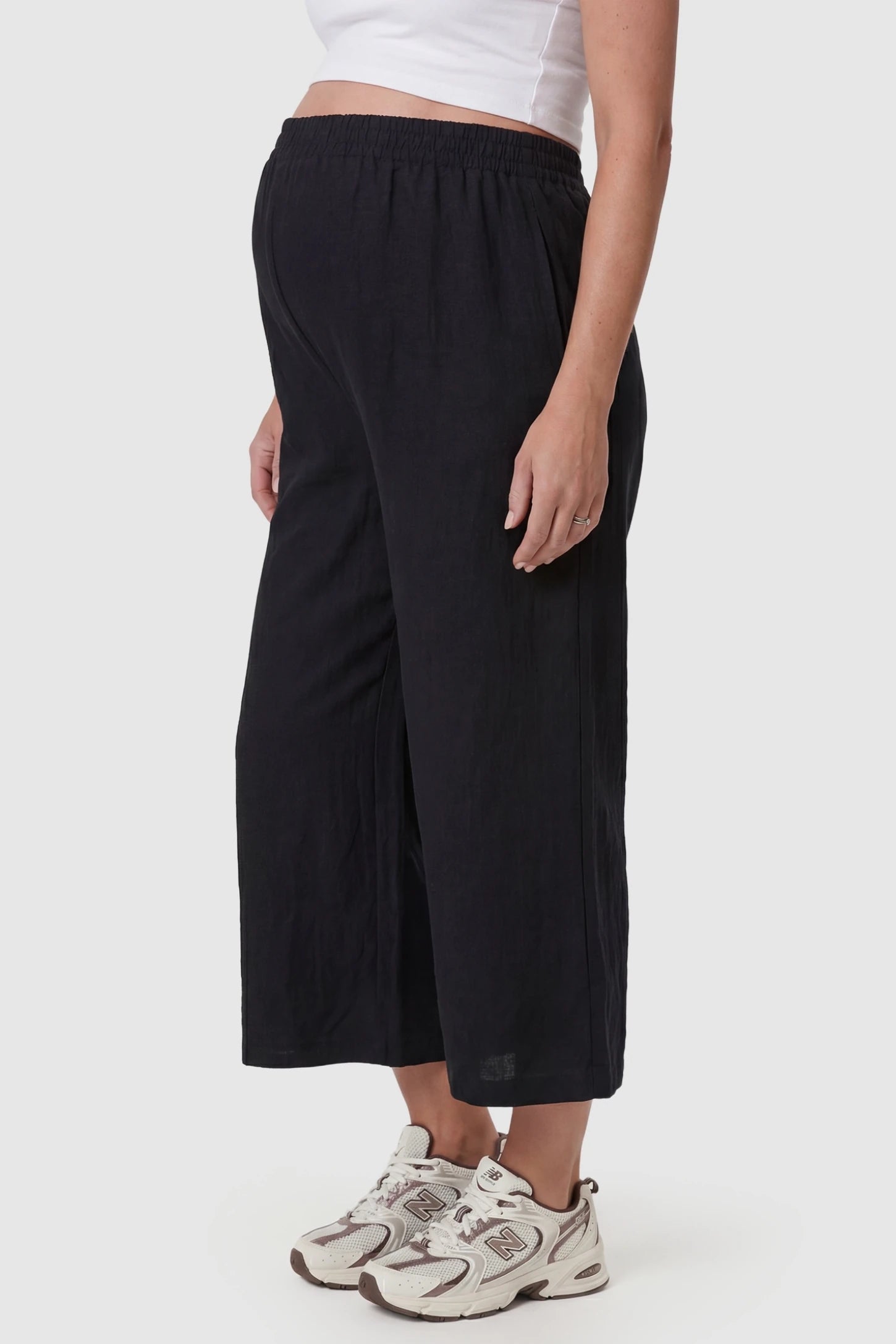 Elastic High Waisted Cropped Maternity Pants Elastic High Waisted Cropped Maternity Pants in Black featuring a high-waisted butt-lifting silhouette on a pregnant model, side view.