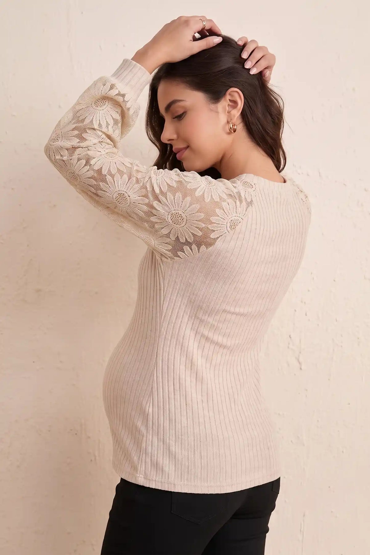 Elegant Openwork Crew Neck Long Sleeve Top Elegant Openwork Crew Neck Long Sleeve Top in Beige featuring delicate floral openwork lace sleeves, soft stretch ribbed knit, and flattering slim fit on a pregnant model, studio back-side pose.