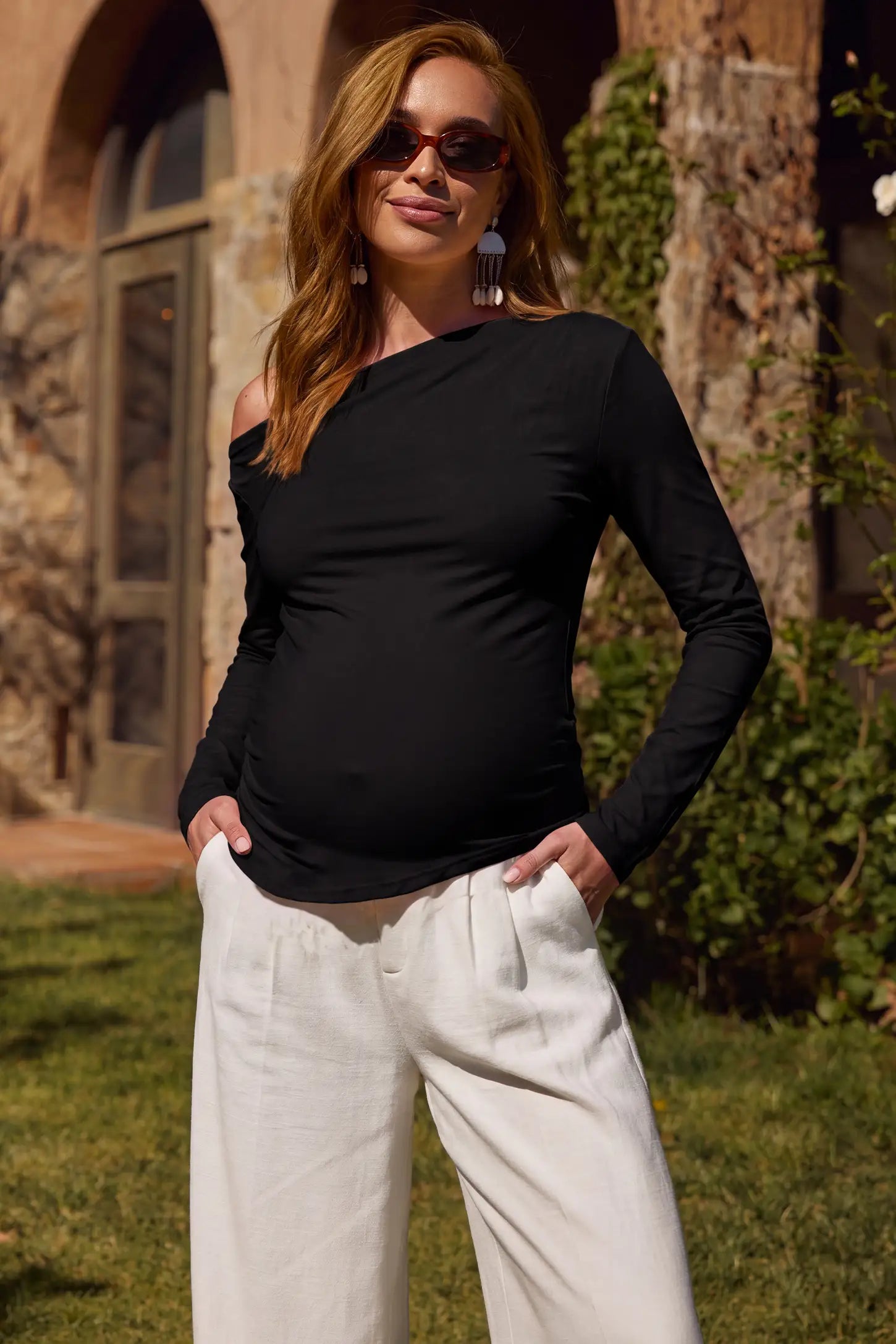 Elegant Black Ruched Side Off-Shoulder Maternity Top Elegant Ruched Side Off-Shoulder Maternity Top in Black featuring a stylish off-shoulder neckline, ruched side details, and soft lightweight fabric on a pregnant model in an editorial lifestyle setting.