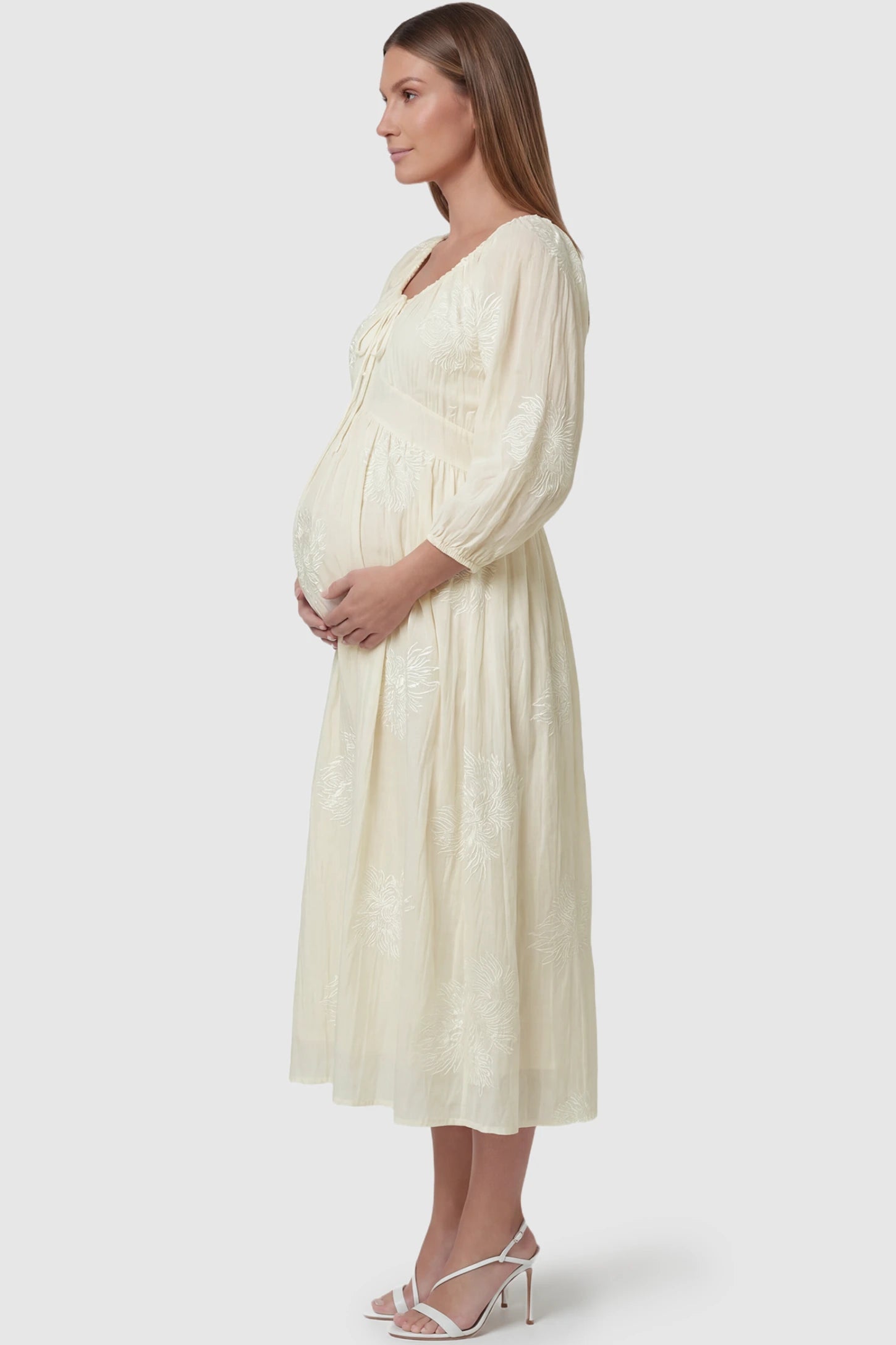 Embroidered Floral Gathered Tie Front Maternity Midi Dress Embroidered floral gathered tie front maternity midi dress in pale yellow with delicate floral embroidery, side view on pregnant model