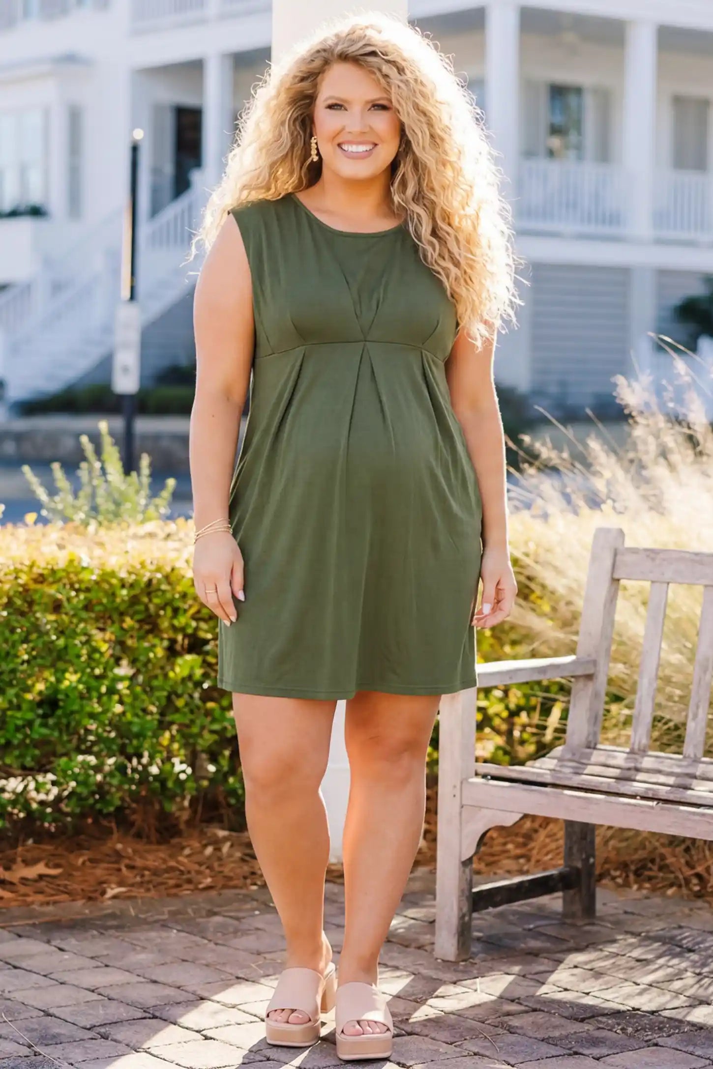Sleeveless Empire Waist Maternity Short Dress Sleeveless empire waist maternity short dress in army green with short length and sleeveless design, front view on pregnant model