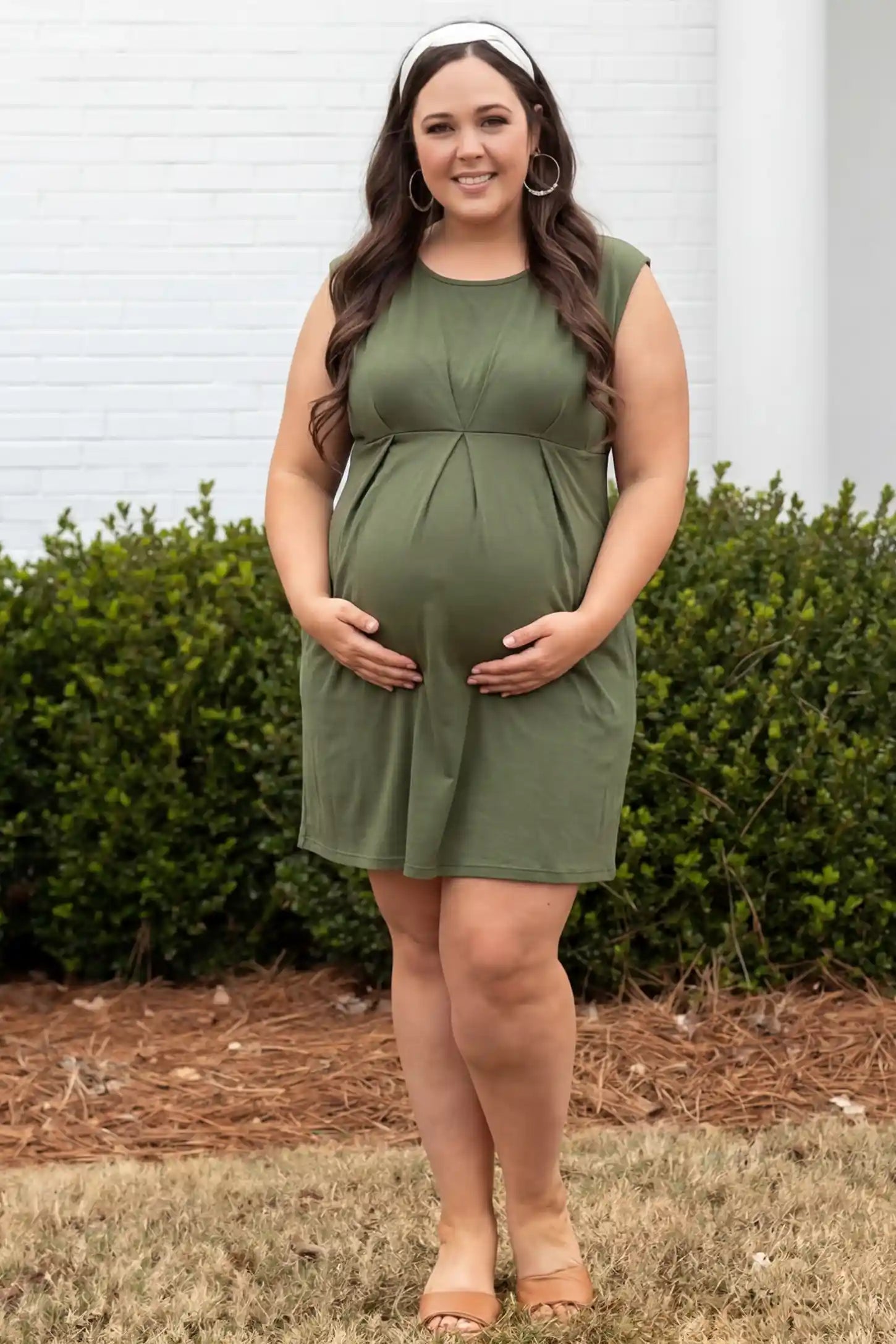 Sleeveless Empire Waist Maternity Short Dress Sleeveless empire waist maternity short dress in army green with short length and sleeveless design, front view on pregnant model