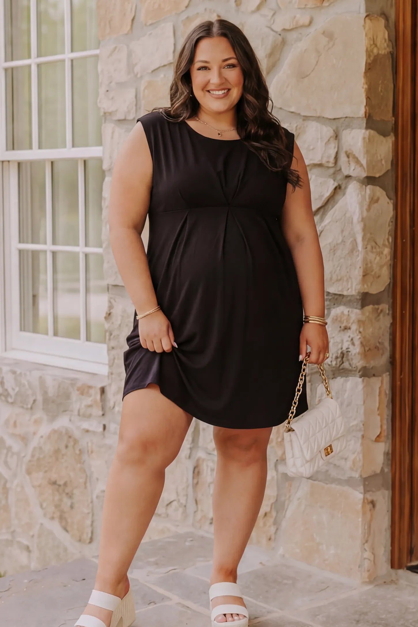 Sleeveless empire waist maternity short dress in black with short length and sleeveless design, front view on pregnant model