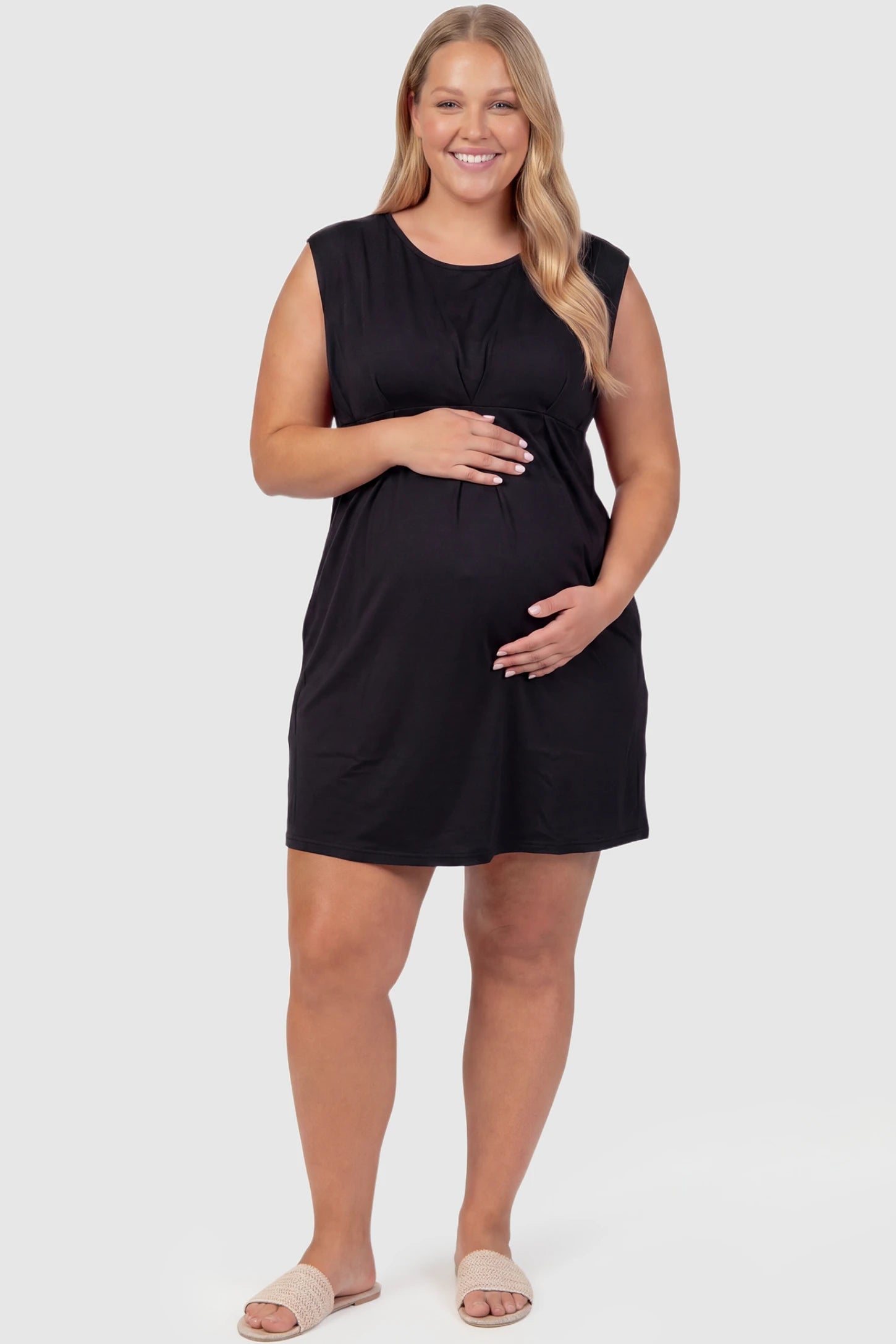 Sleeveless Empire Waist Maternity Short Dress Sleeveless empire waist maternity short dress in black with short length and sleeveless design, front view on plus-size model