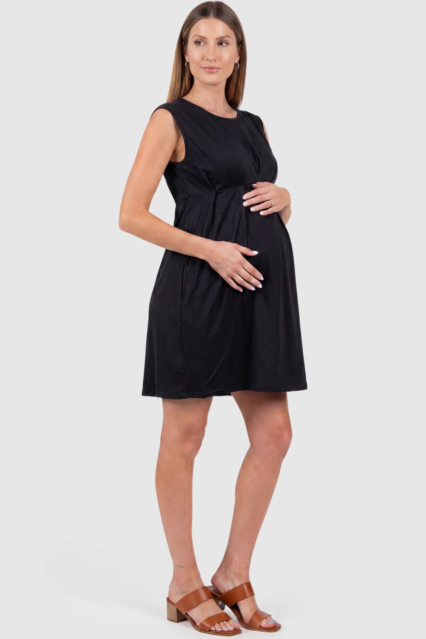 Sleeveless Empire Waist Maternity Short Dress Sleeveless empire waist maternity short dress in black with short length and sleeveless design, side view on pregnant model