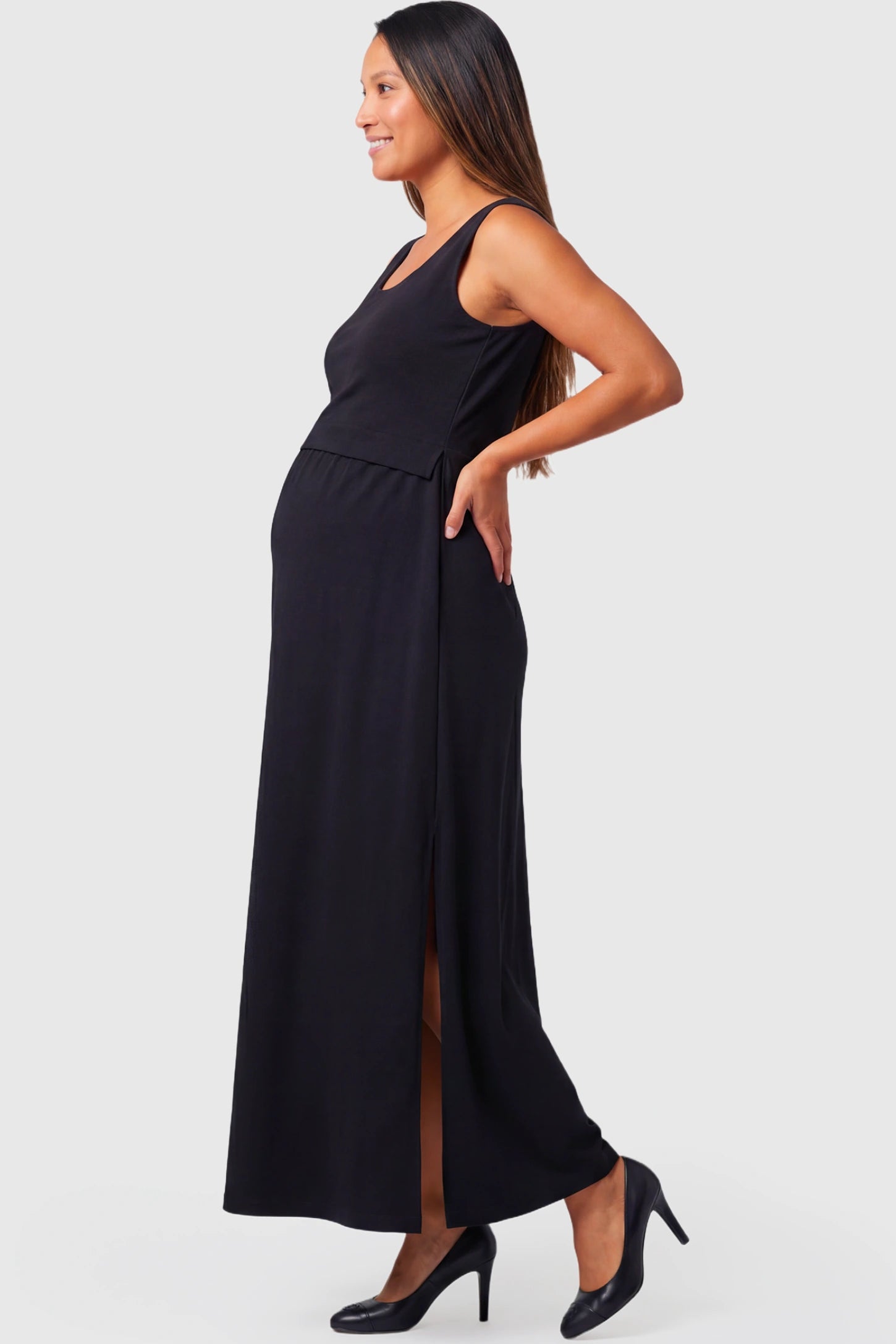 Sleeveless Empire Waist Maternity & Nursing Maxi Dress in black featuring side slit, fitted bodice, and flowing A-line silhouette on a pregnant  model.