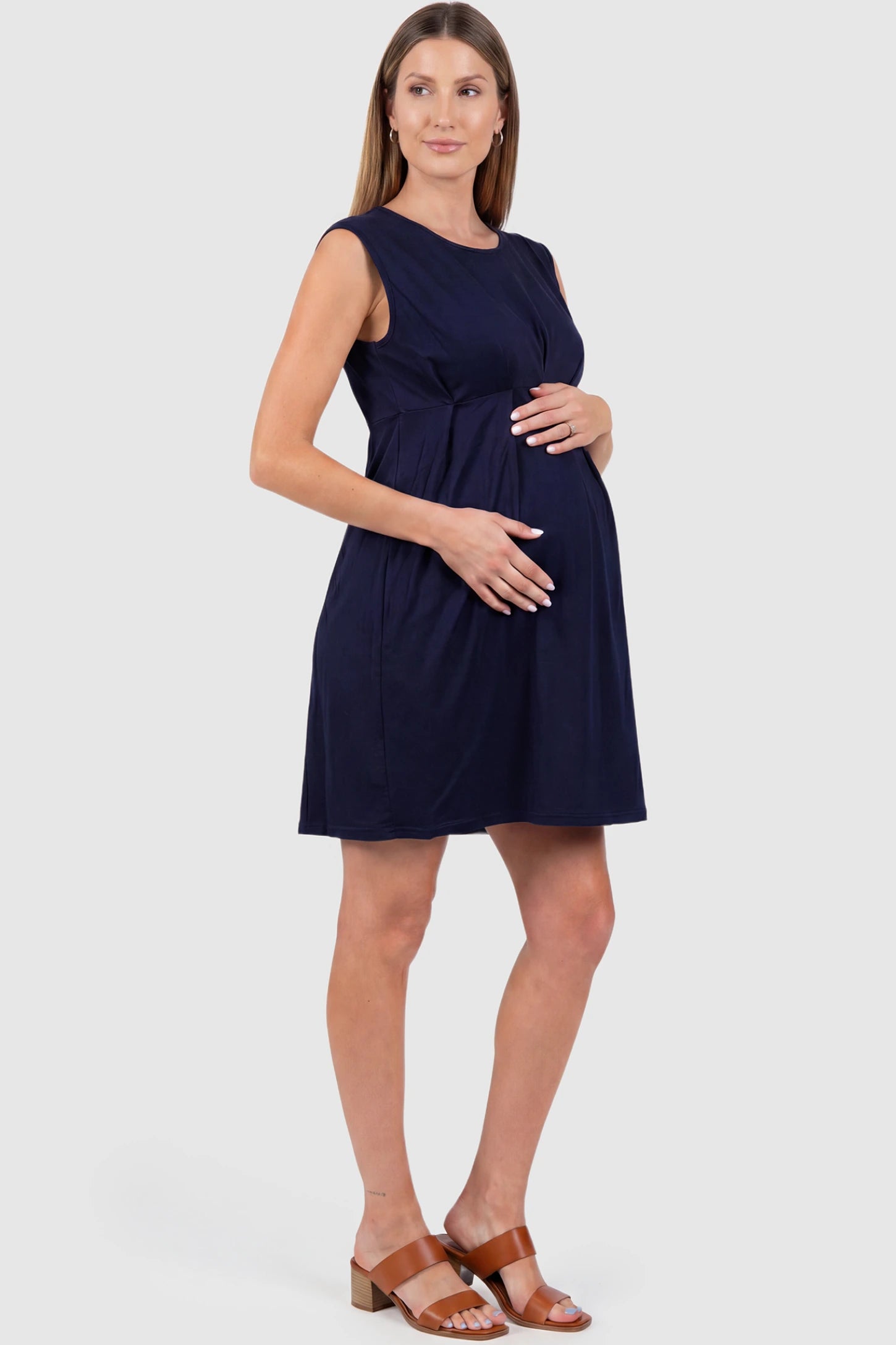 Sleeveless Empire Waist Maternity Short Dress Sleeveless empire waist maternity short dress in navy blue with short length and sleeveless design, side view on pregnant model