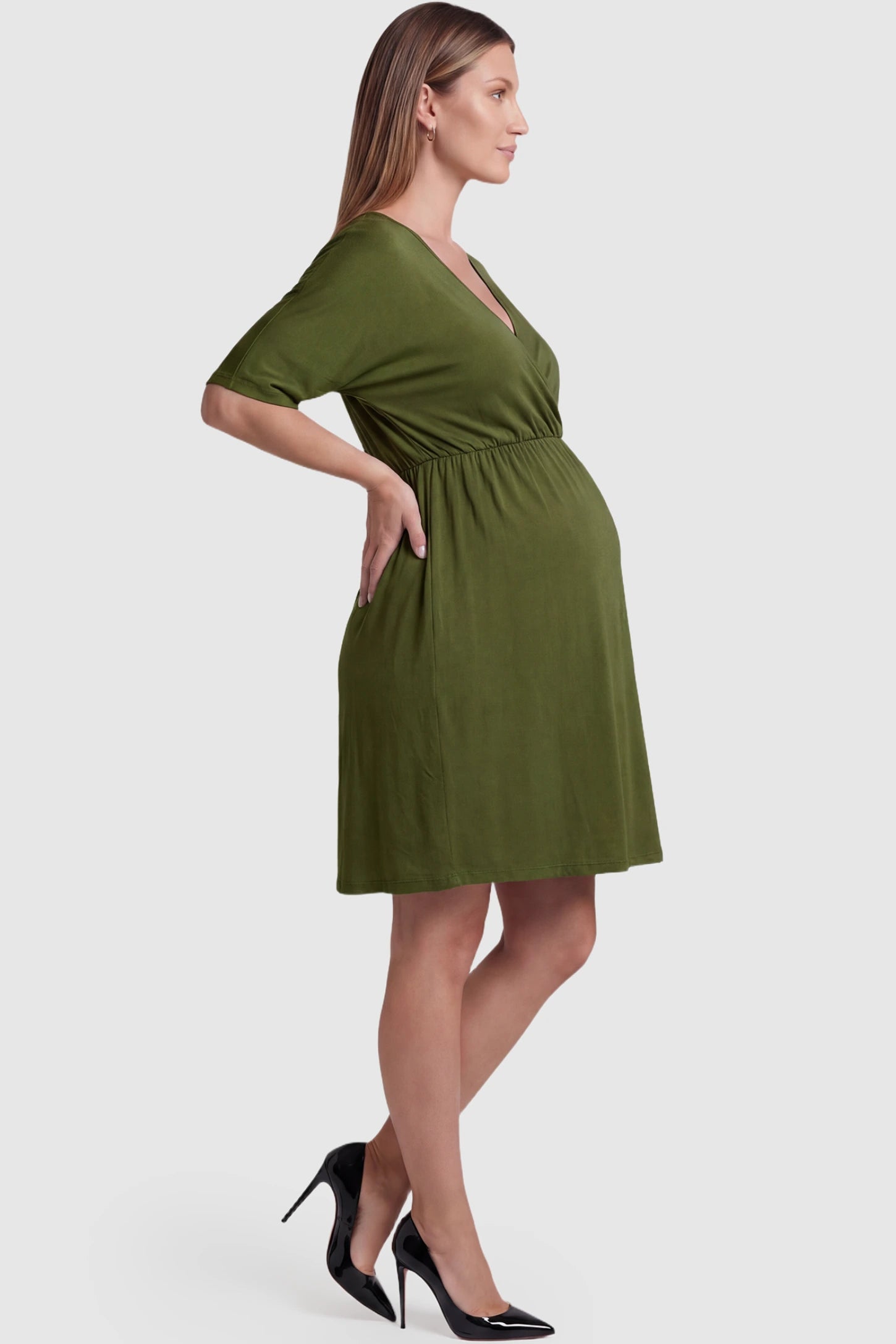Wrap Front Empire Waist Maternity & Nursing Mini Dress Wrap Front Empire Waist Maternity & Nursing Dress in army green featuring a draped crossover V-neck and short sleeves on pregnant model side view.
