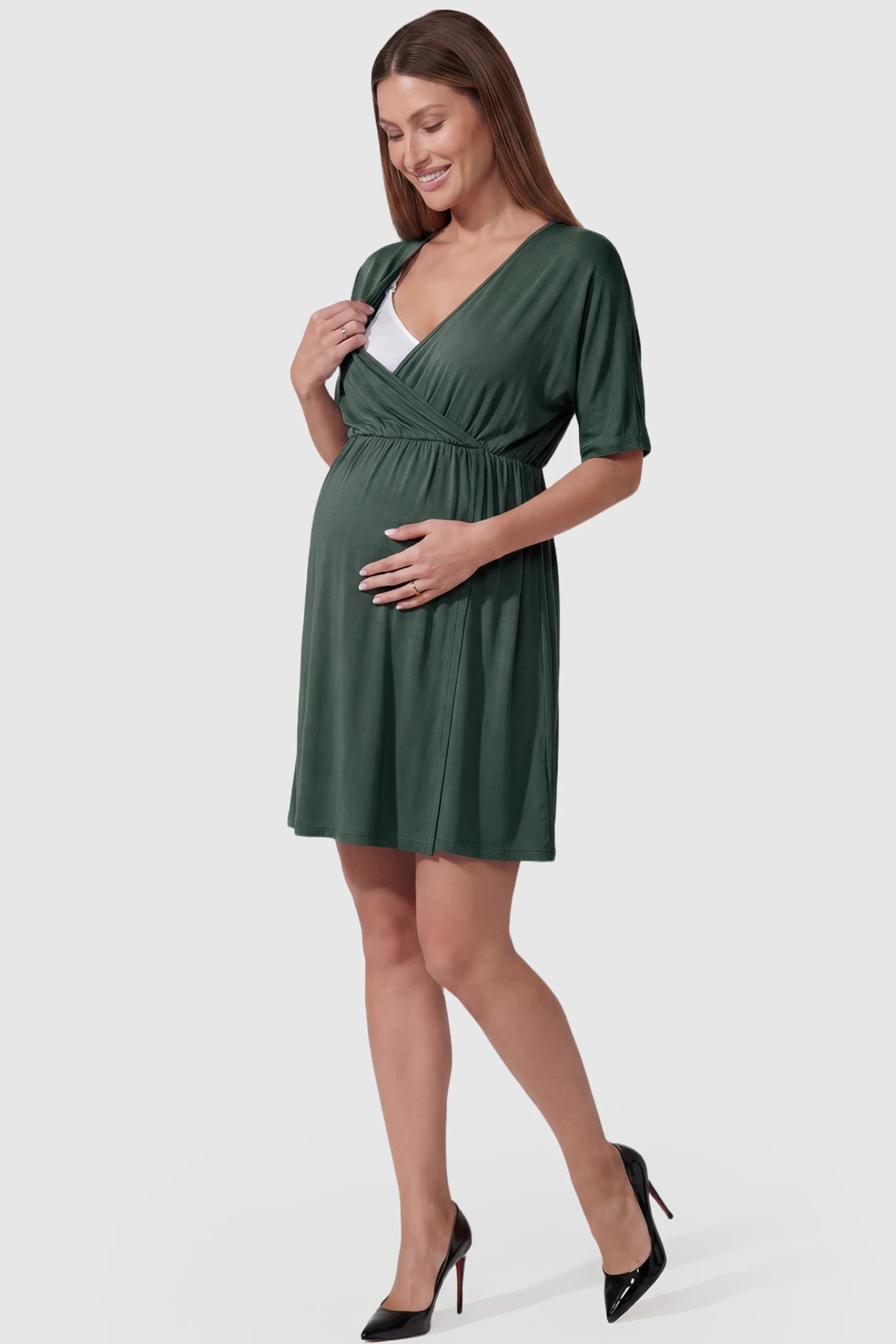Wrap Front Empire Waist Maternity & Nursing Mini Dress Wrap Front Empire Waist Maternity & Nursing Dress in dark green featuring a draped crossover V-neck and short sleeves on pregnant model.