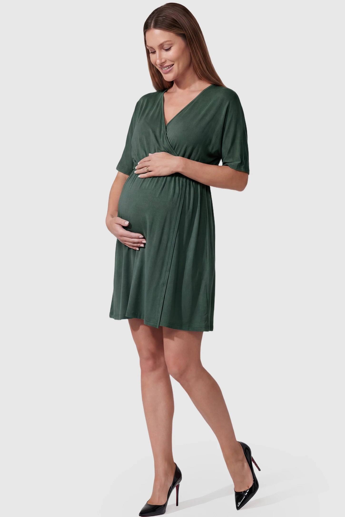 Wrap Front Empire Waist Maternity & Nursing Dress in dark green featuring a draped crossover V-neck and short sleeves on pregnant model front view.
