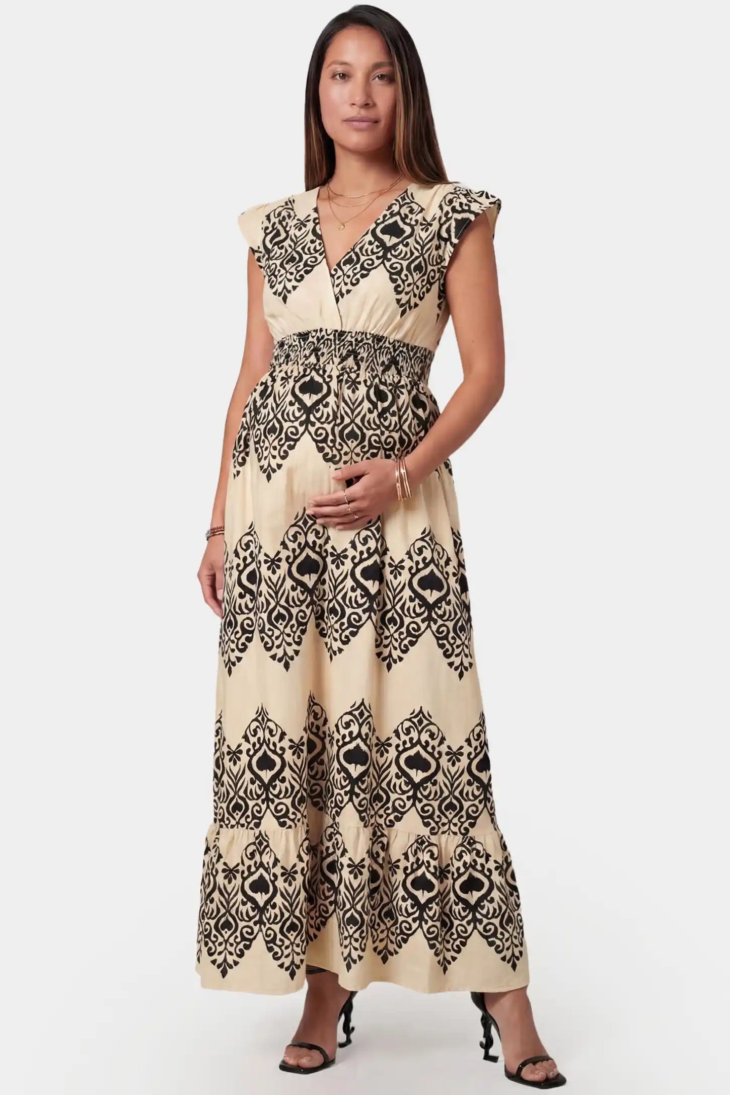 Ethnic print V-neck cap sleeve A-line maxi maternity dress in beige featuring ethnic print and V-neckline in front view on a pregnant model