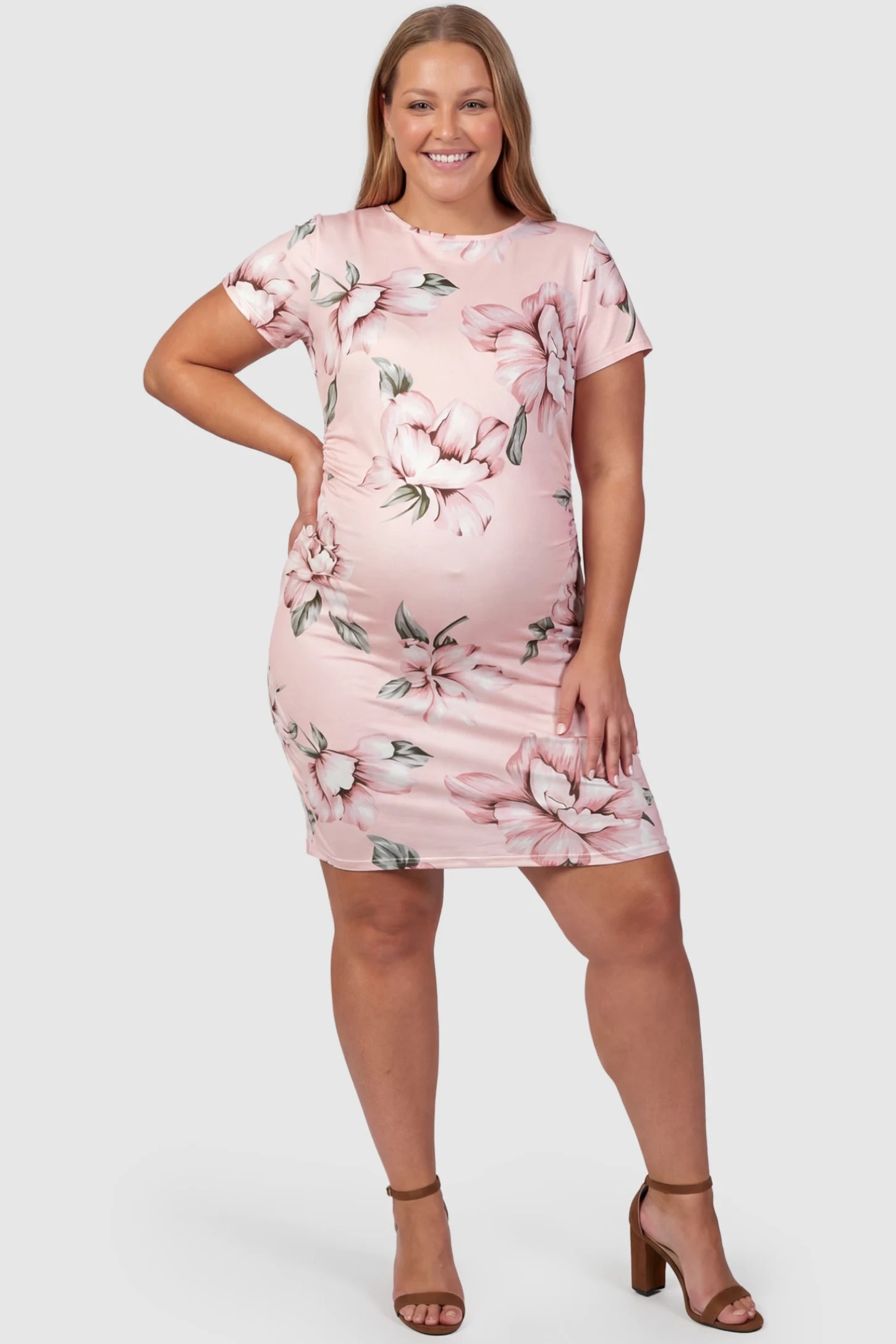 Floral Ruched Bodycon Maternity Short Dress Floral Ruched Bodycon Maternity Short Dress in pink floral featuring side ruching on plus size pregnant model, front view.
