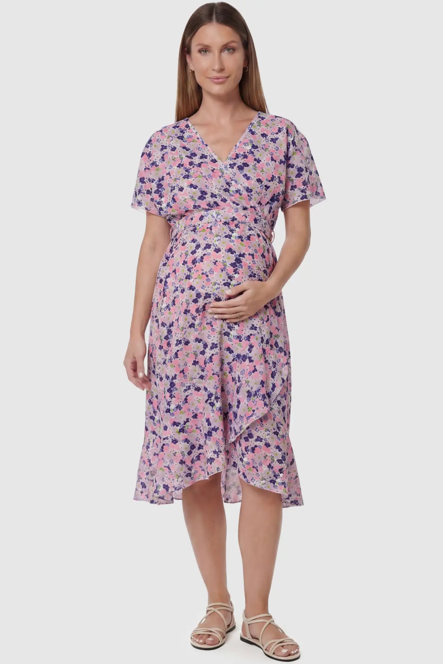 Floral V-neck ruffled hem midi maternity dress in apricot featuring V-neckline and tie waist in full body front view on a pregnant model, front view.