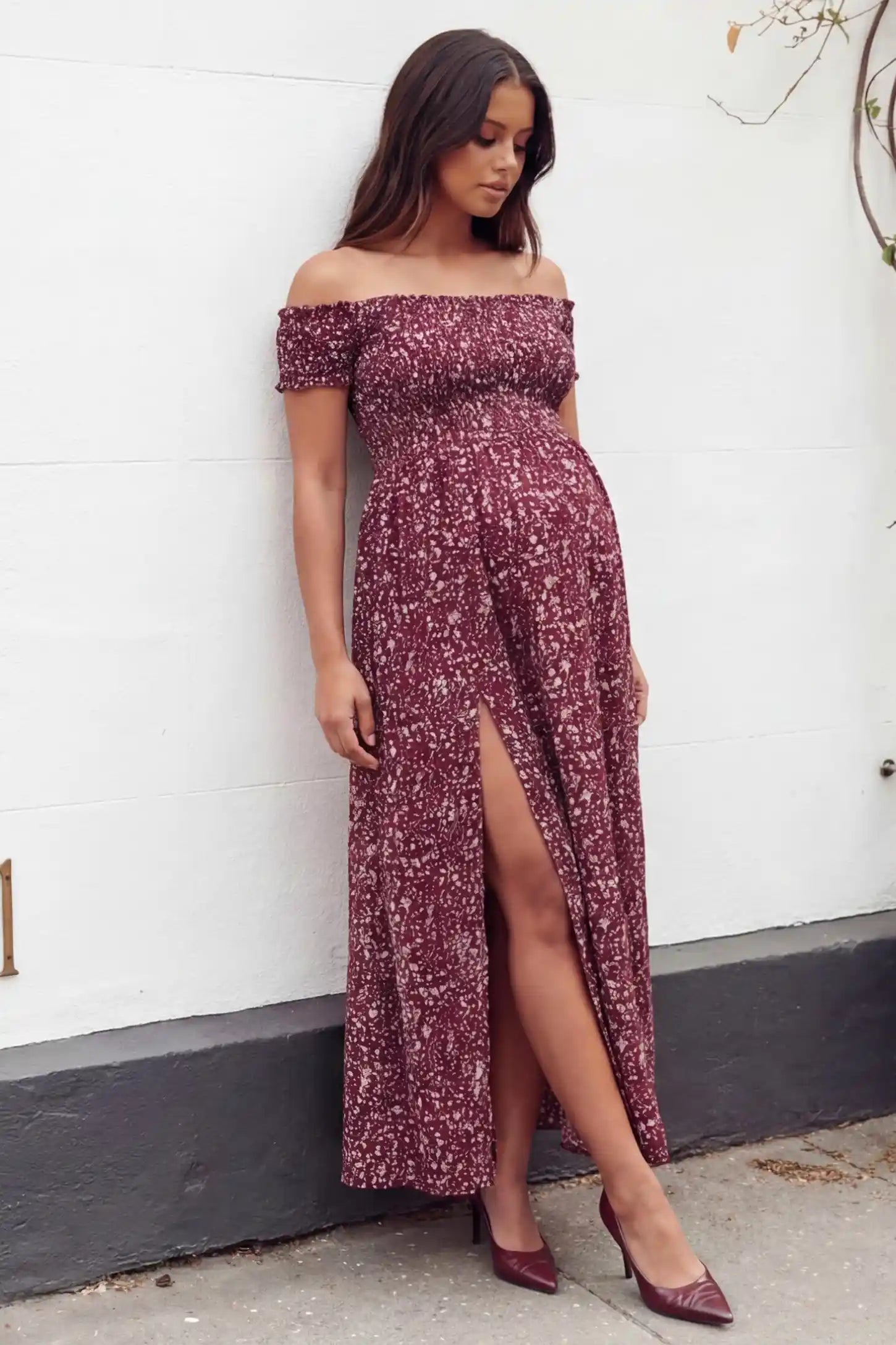 Floral off-shoulder smocked bodice maxi maternity dress in burgundy featuring smocked neckline in front view on a editorial lifestyle model